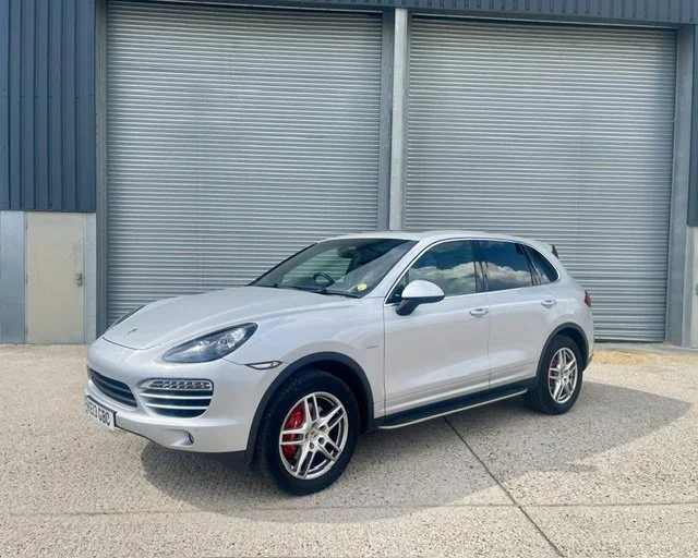SILVER PORSCHE  SUV AGAINST A METAL BACKGROUND