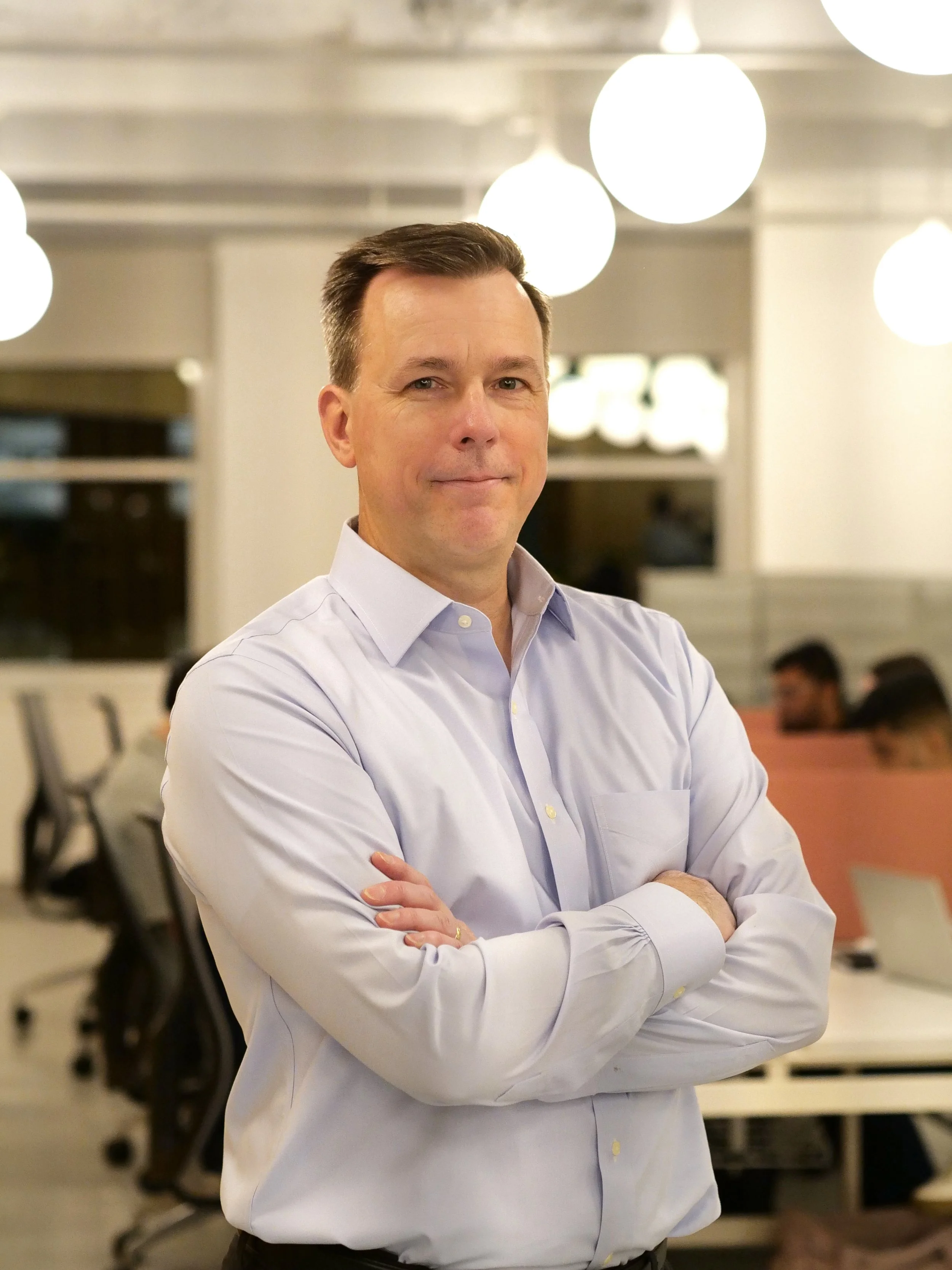 Professional portrait of a man in a suit with an urban cityscape background.
