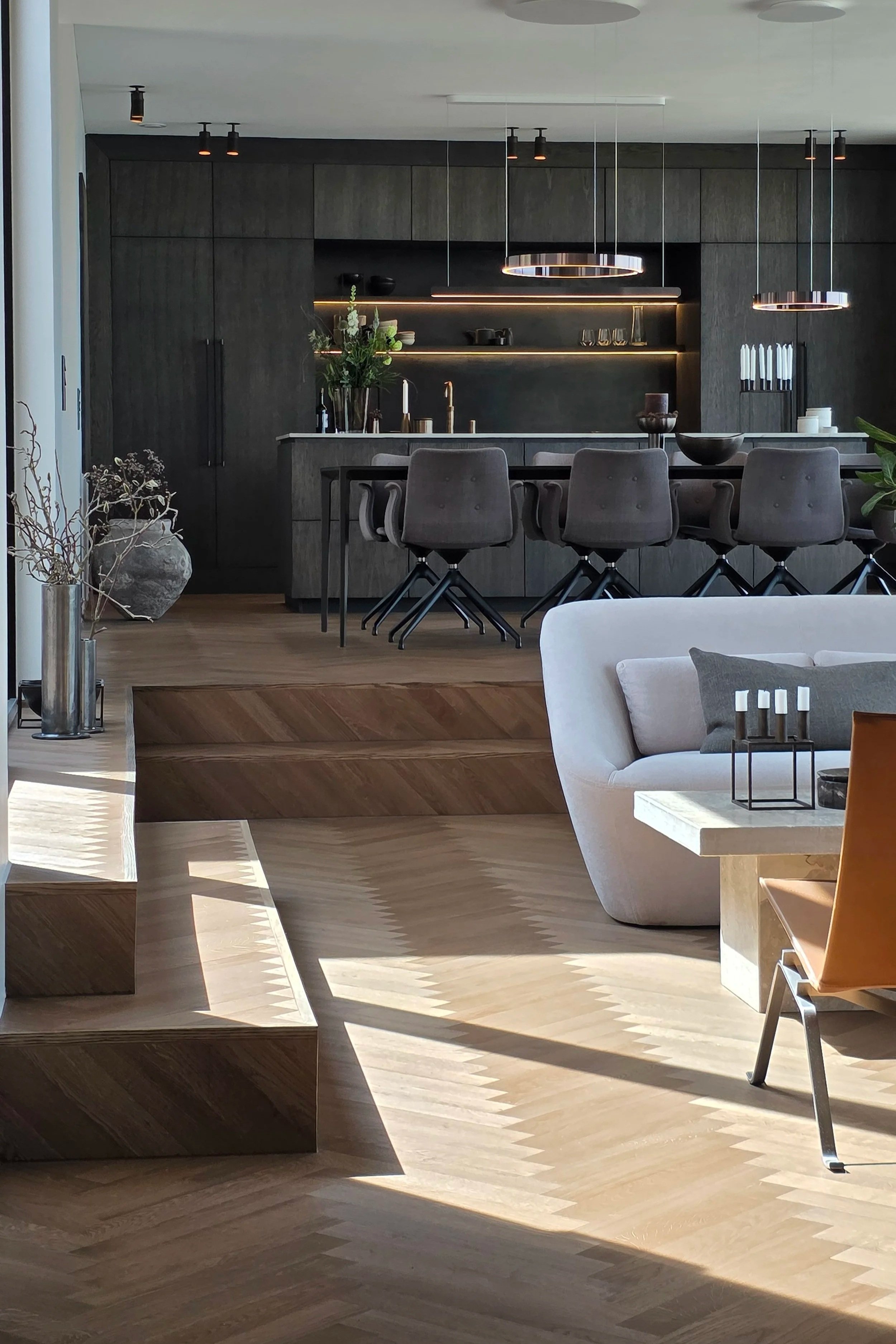 Nordic house interior featuring Scandinavian architecture with dark wood cabinetry, wood flooring, minimalist kitchen design and warm natural light.