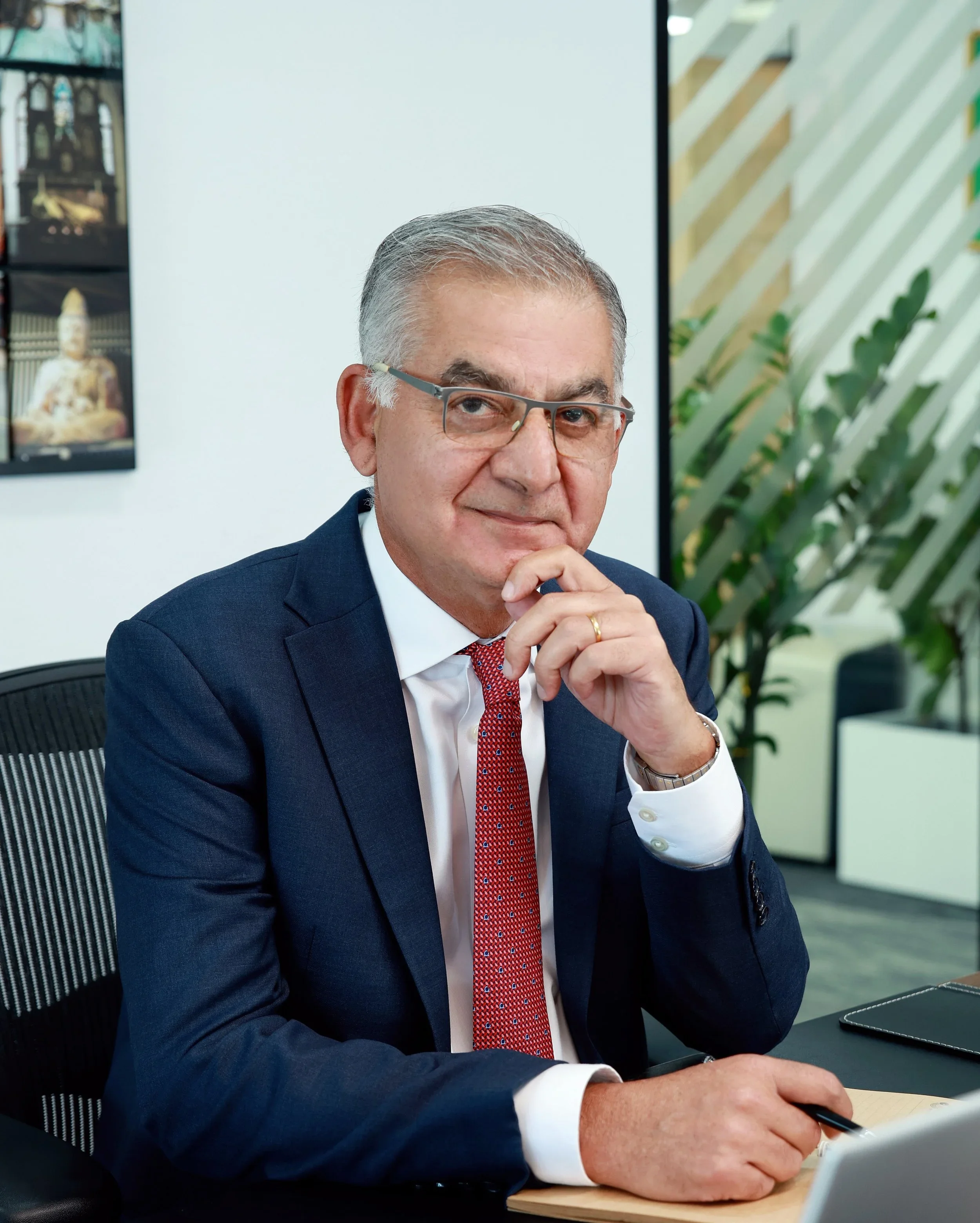 Man wearing glasses and a dark blazer speaking into a microphone during a panel discussion, with another person partially visible.