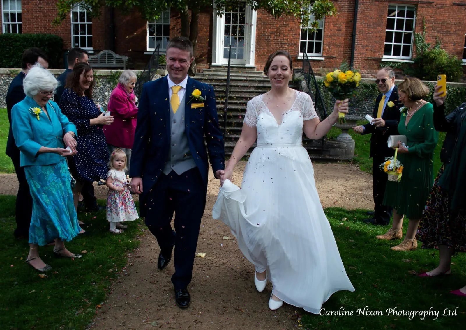 Berkshire wedding photographer capturing bride and groom walking hand in hand with confetti at Leatherhead Register Office