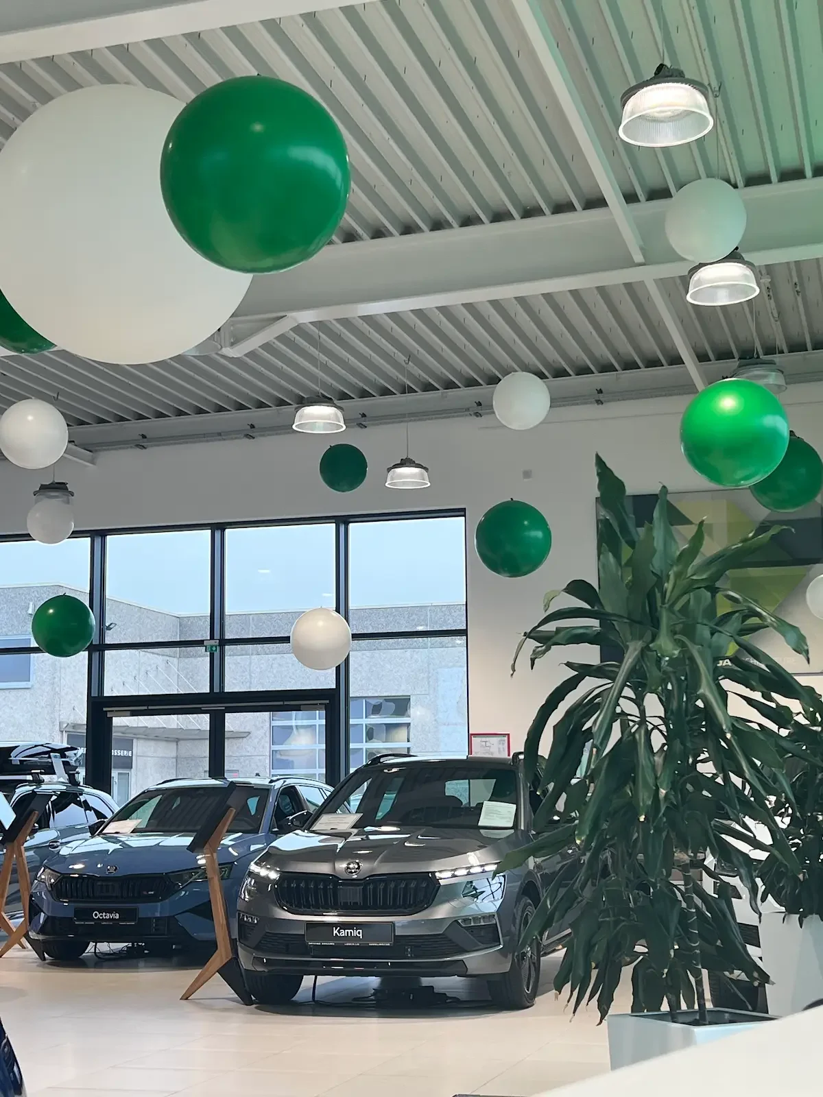 Balloon decorations in blue, white, and silver at a party with a balloon arch, star-shaped balloons, and a backdrop. Large helium balloons with mustache and bowtie designs are floating, some with smaller balloons inside.