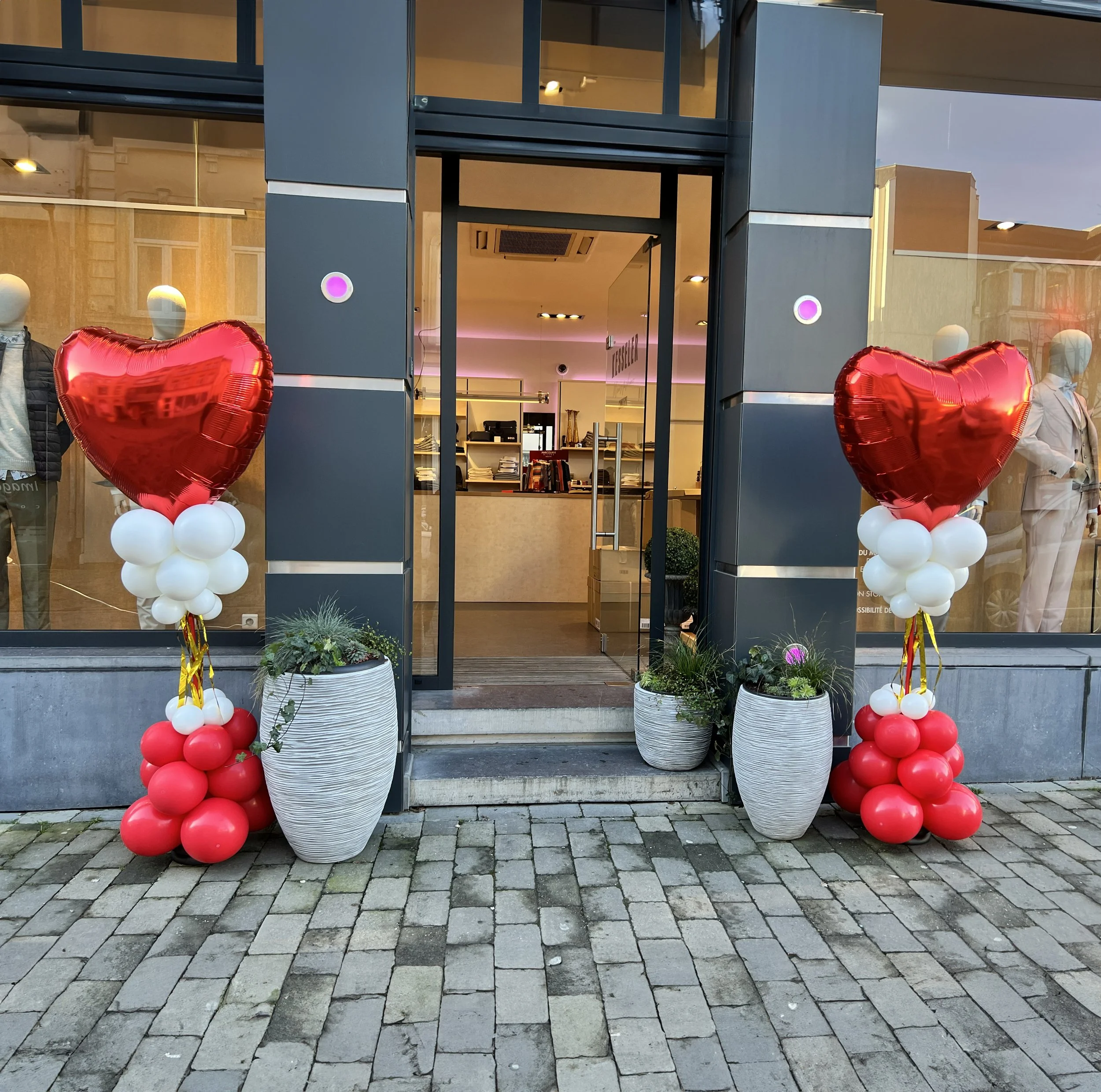 Elegant interior decorated for a celebration with white balloon arrangements and a table set for dining.
