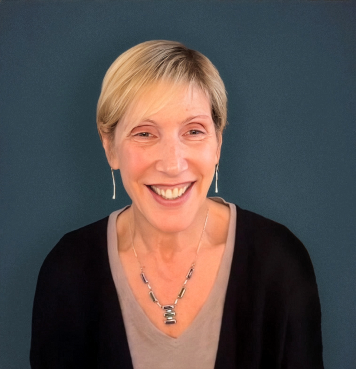 A headshot photo of author and podcast host, Wendy Lurrie, smiling against a solid blue-gray background.