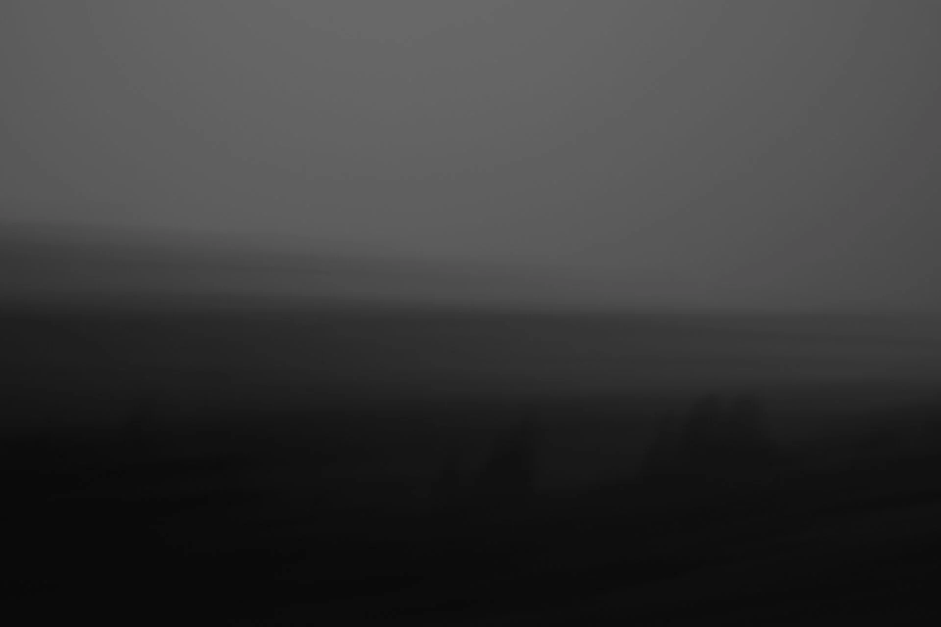 A dark, blurred scene in grayscale with no distinguishable objects or features.