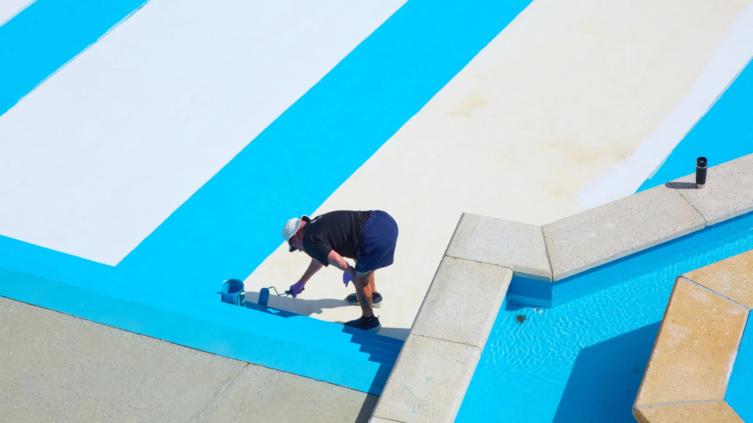 Photograph of a solitary worker repainting the edge of Tinside Lido