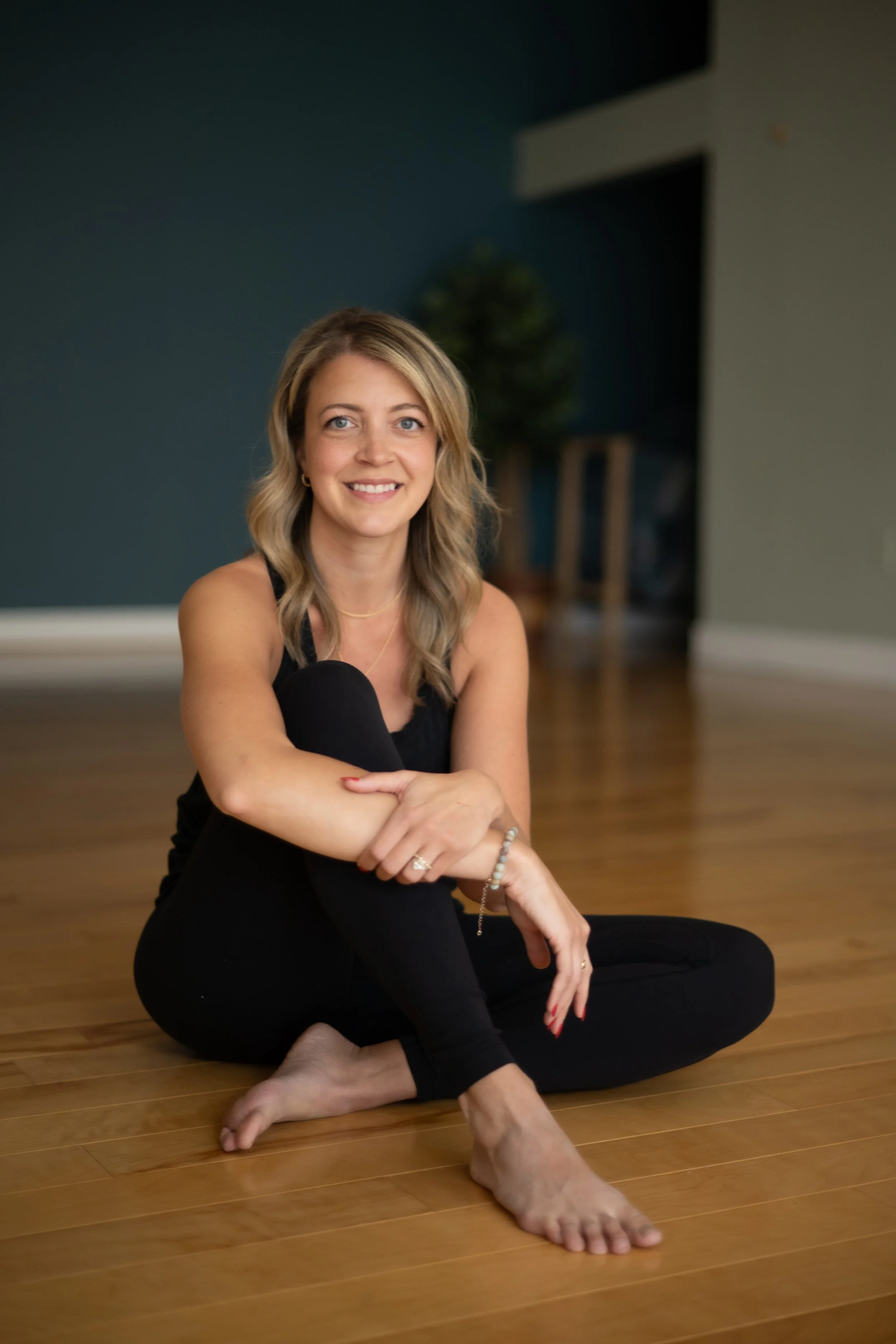 Anne-Marie Kida, owner of New Moon Yoga Studio in Franklin Tn, seated in a peaceful yoga pose on the studio floor, embodying mindfulness and stillness.