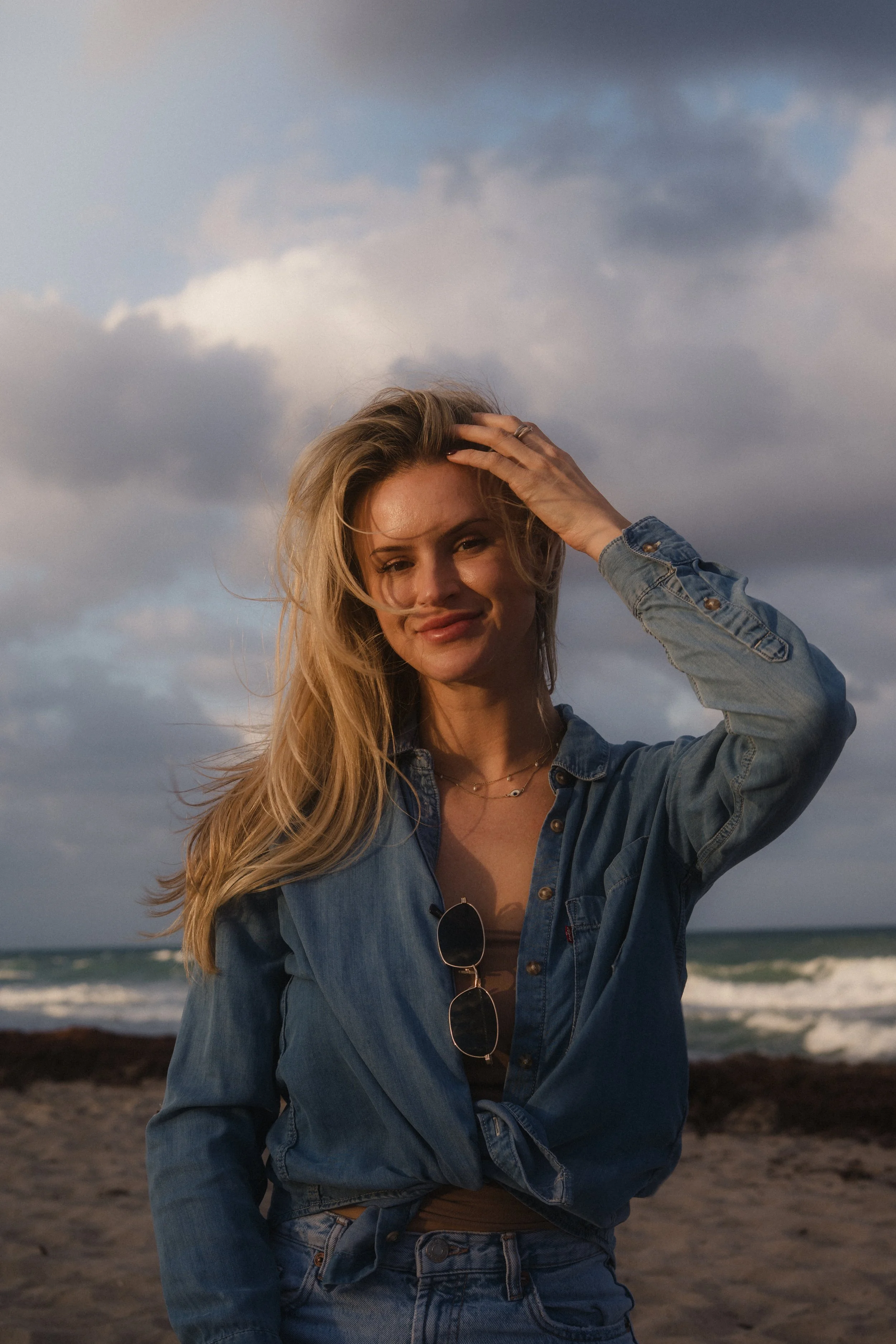 woman with blonde hair at the beach with wing blown hair