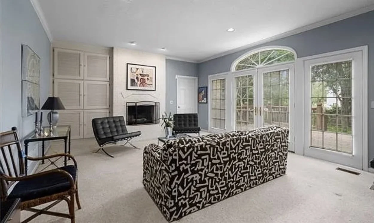 Outdated 1990's hearth room with fireplace, old furniture and carpet.