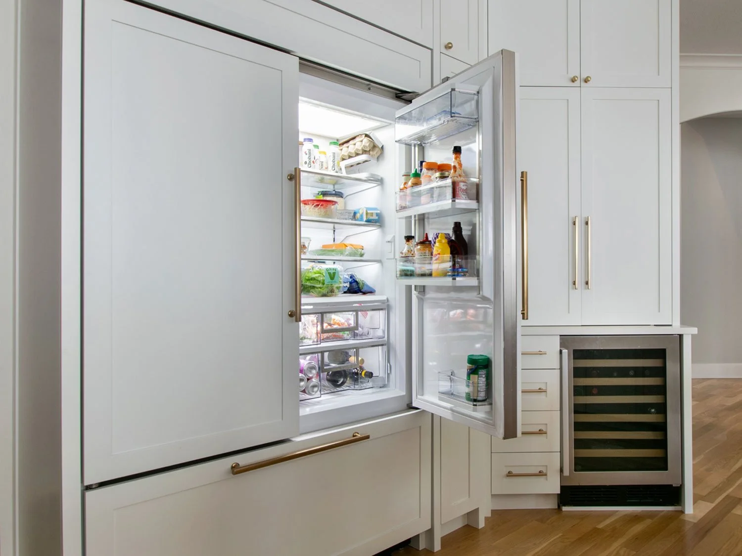 Panel-ready integrated refrigerator surrounded by ceiling-height white cabinetry.