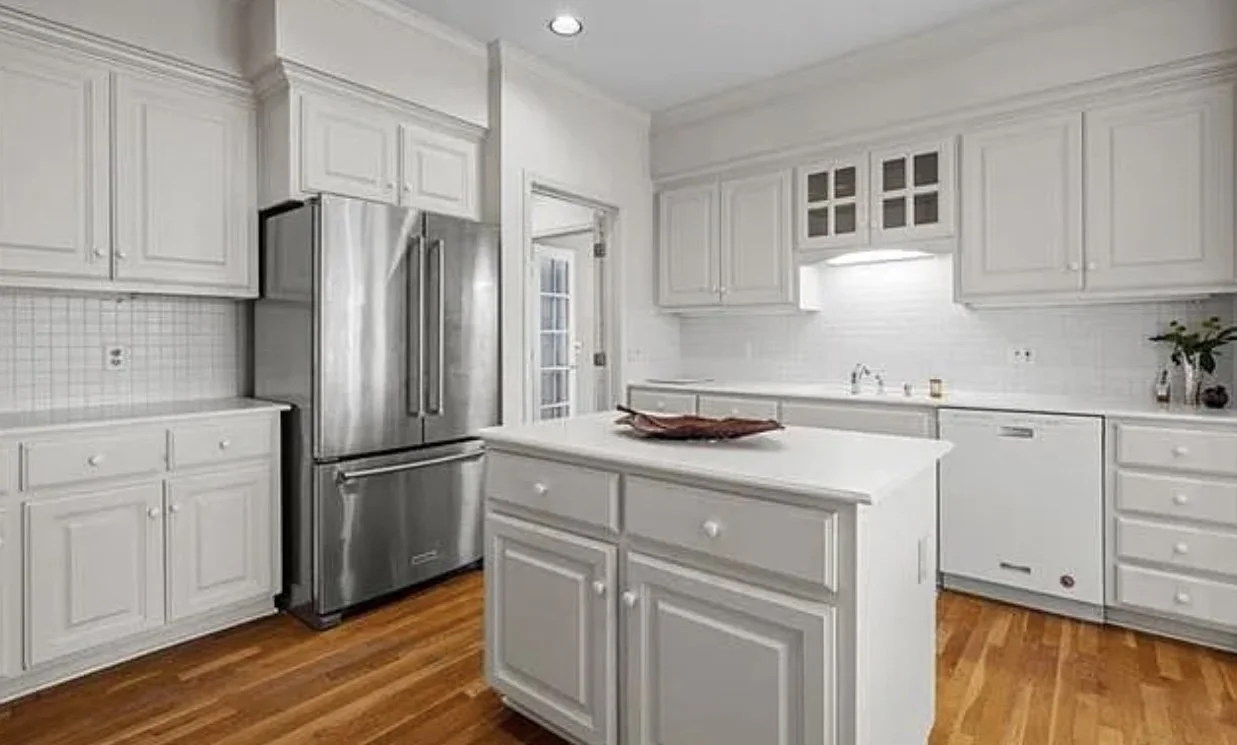 Outdated 1990's kitchen, all white shaker cabinets, and soffit.