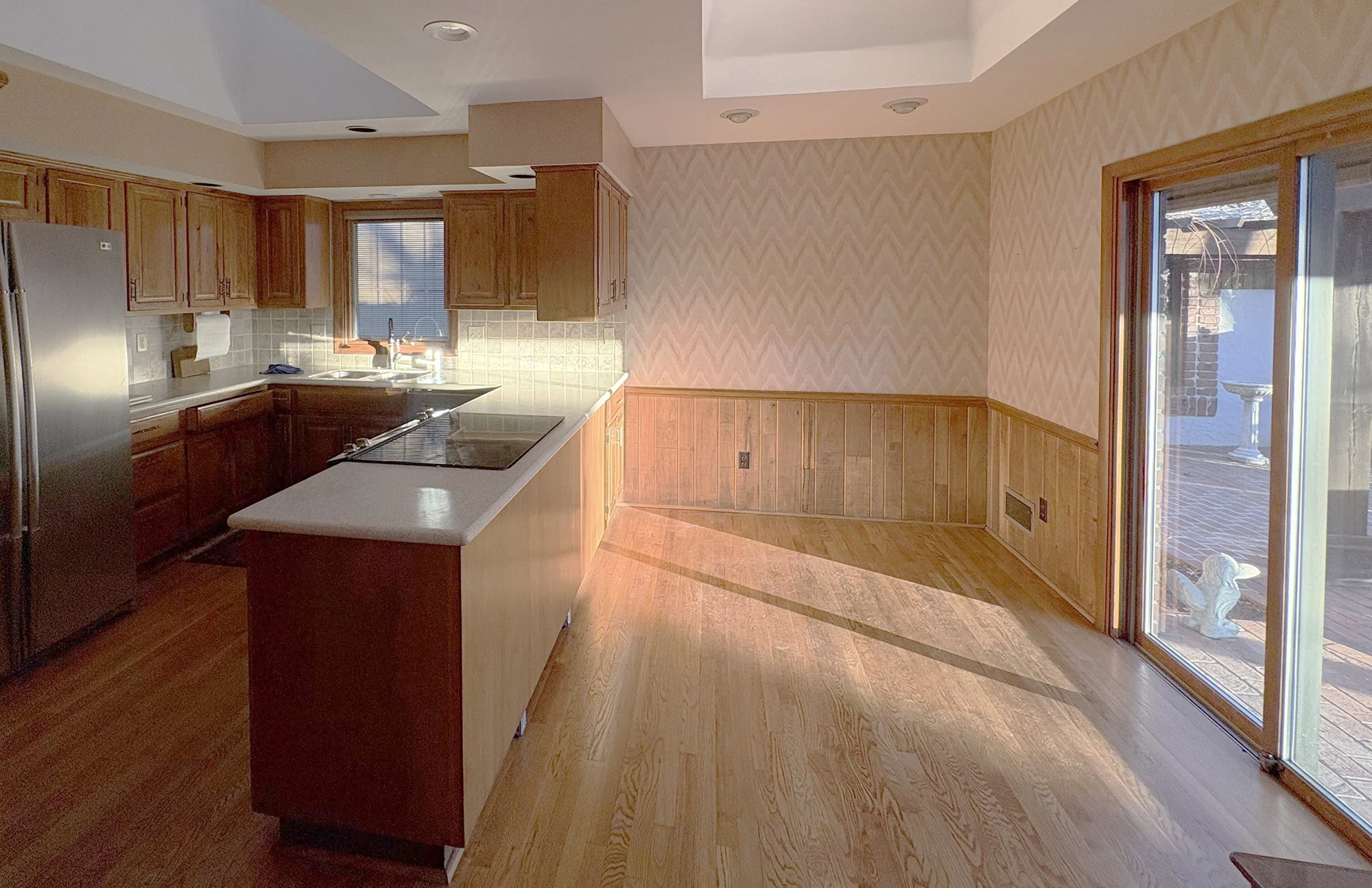 Prairie Village kitchen before renovation, with wood cabinetry, a cooktop peninsula, and two large skylights.