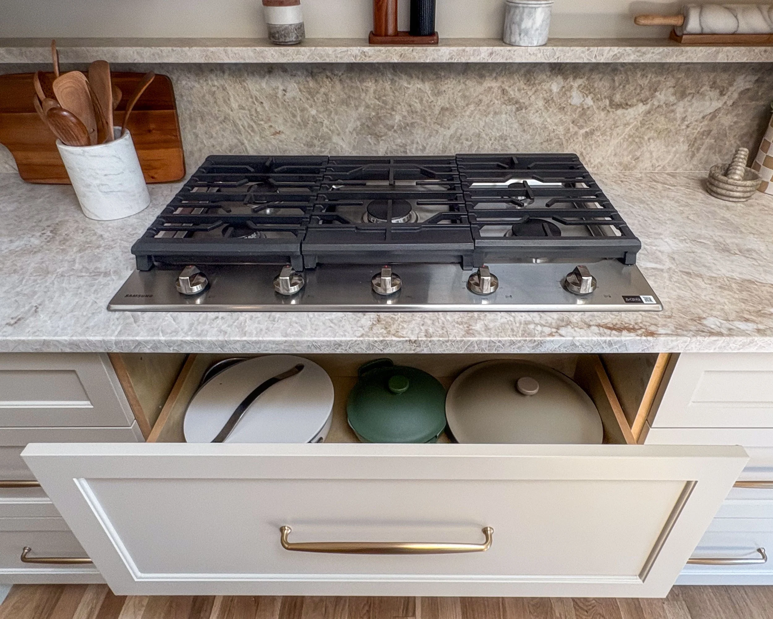 Leathered Taj Mahal countertop and matching stone ledge above painted kitchen cabinetry.