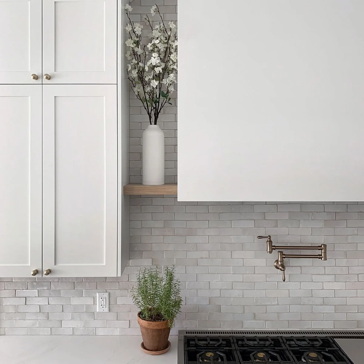 Pro-style range and pot filler framed by white cabinetry and a handmade Clé tile backsplash.
