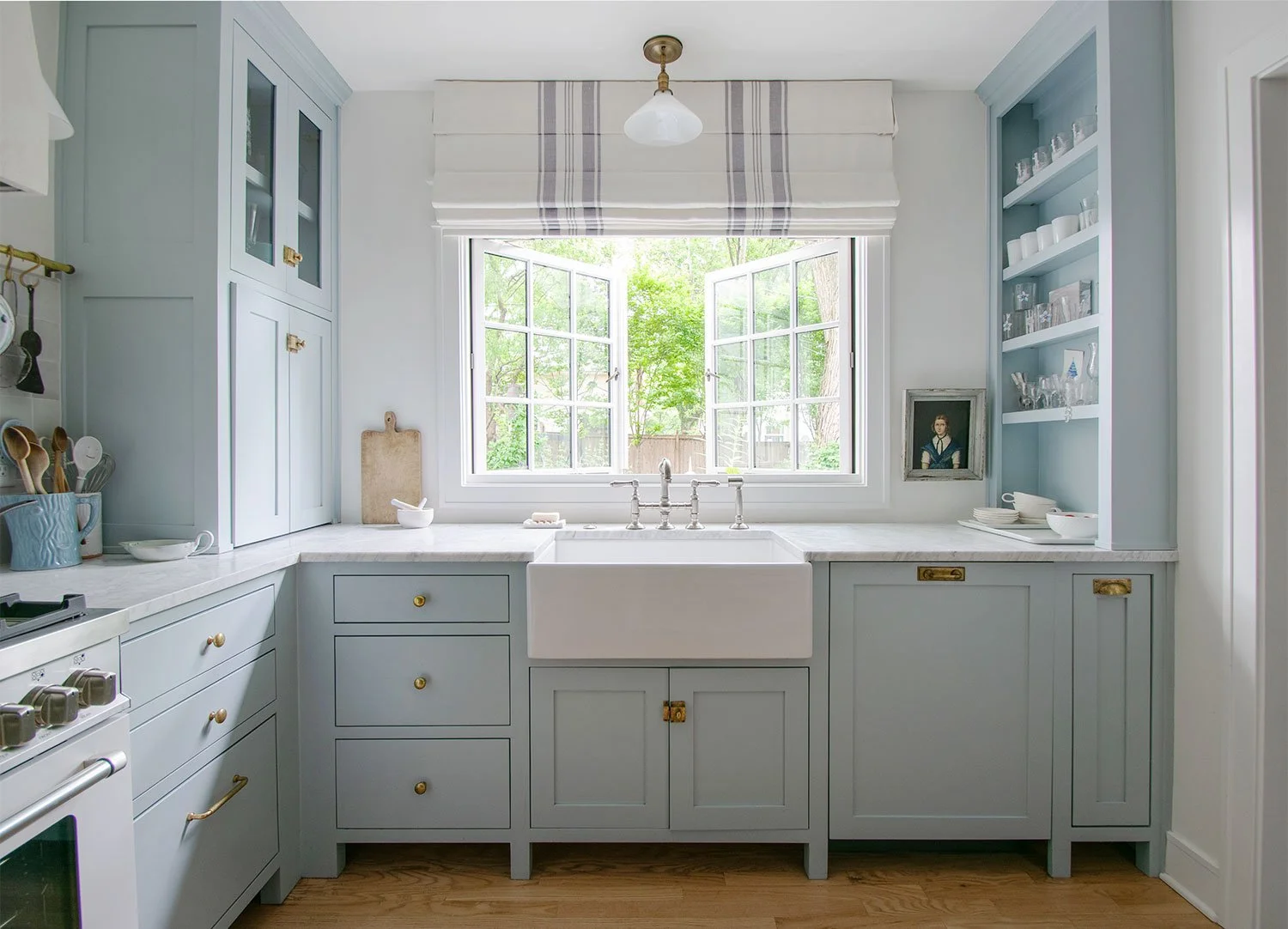 Inset kitchen cabinetry in Fairway, Kansas featuring soft blue-gray cabinets, a farmhouse sink, marble countertops, and timeless European-inspired detailing by Erica Kay Design & Remodeling.