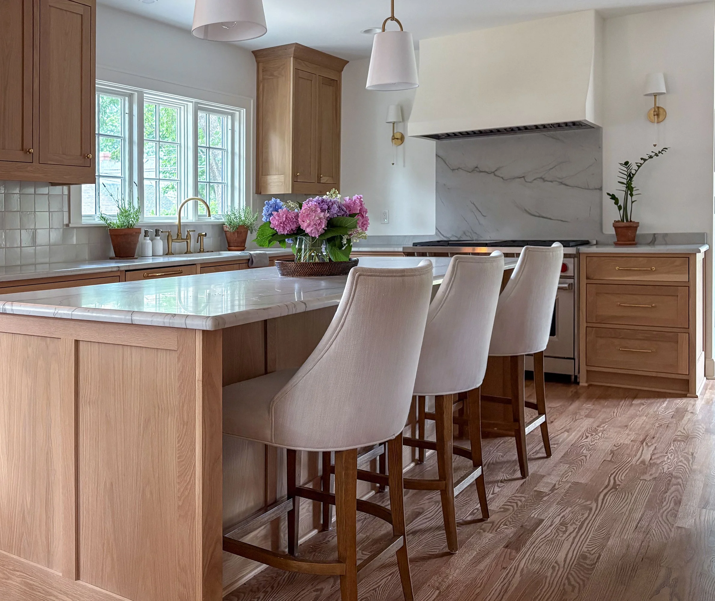 Kitchen renovation in the Brookside neighborhood of Kansas City, Missouri featuring custom wood cabinetry, a marble island countertop, classic range alcove, and warm, timeless detailing by Erica Kay Design & Remodeling.