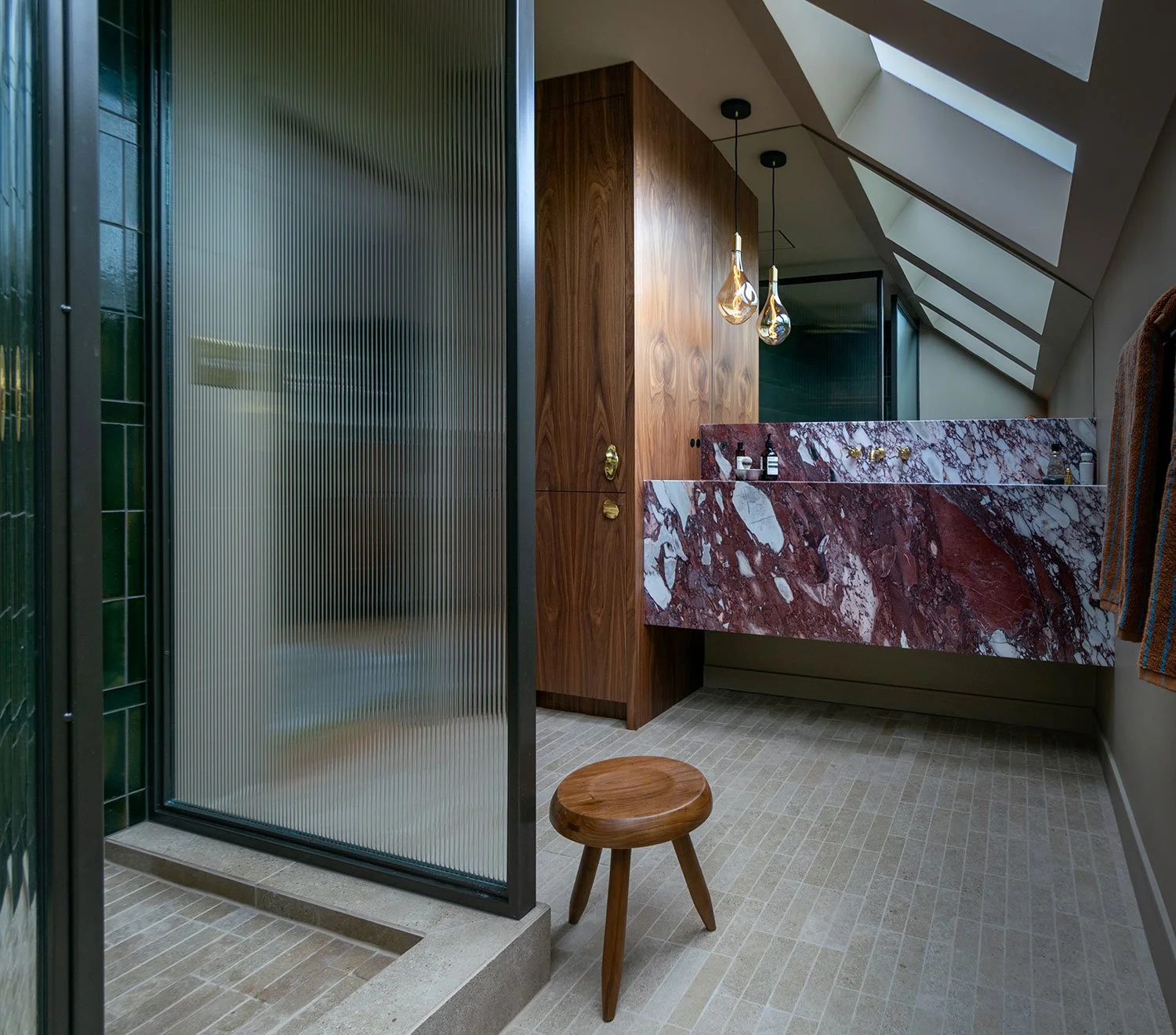 Modern bathroom remodel in Kansas City featuring a floating marble vanity, custom walnut cabinetry, fluted glass shower enclosure, and skylight detailing by Erica Kay Design & Remodeling.