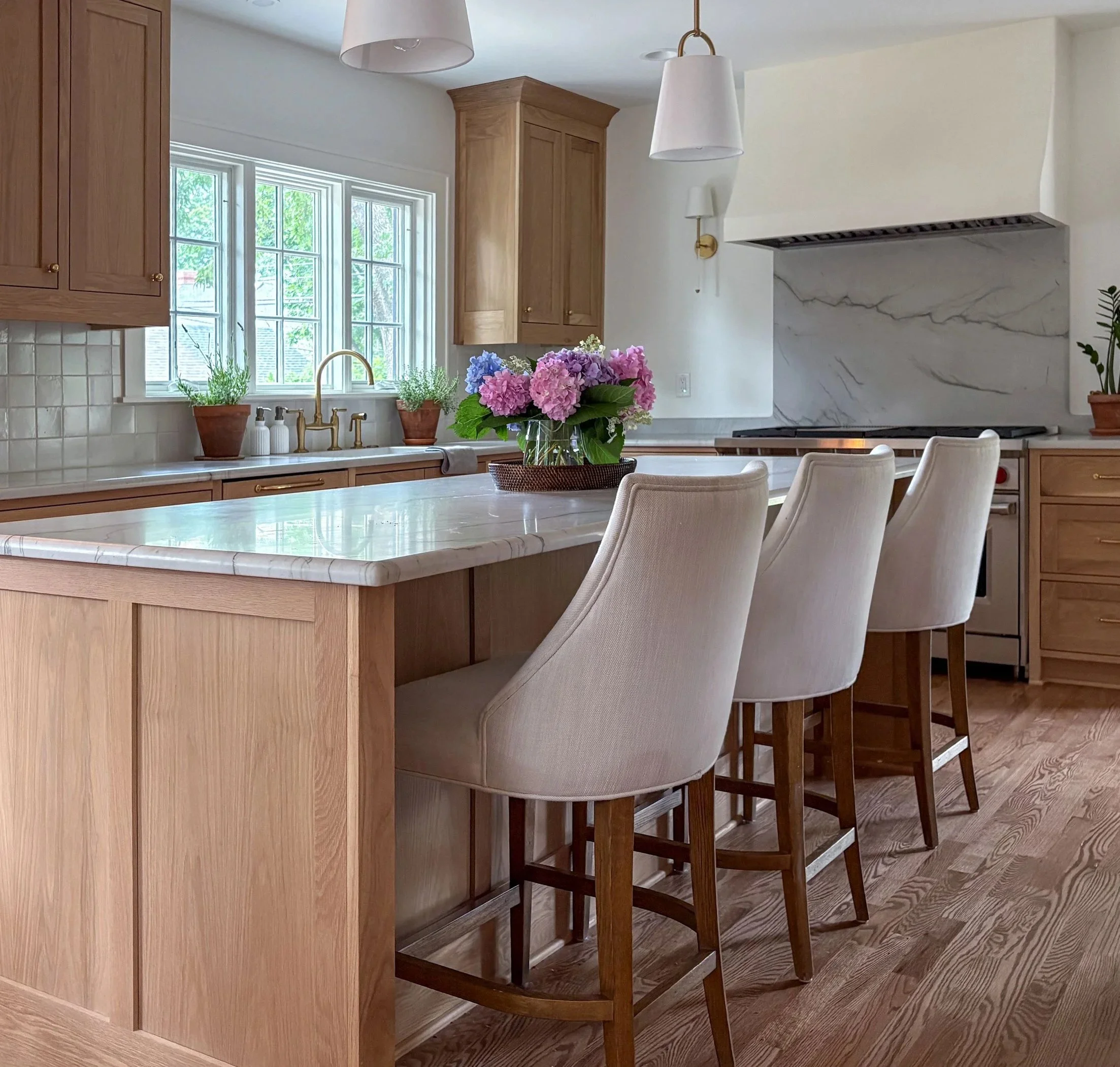 Kitchen renovation in the Brookside neighborhood of Kansas City, Missouri featuring custom wood cabinetry, a marble island countertop, classic range alcove, and warm, timeless detailing by Erica Kay Design & Remodeling.