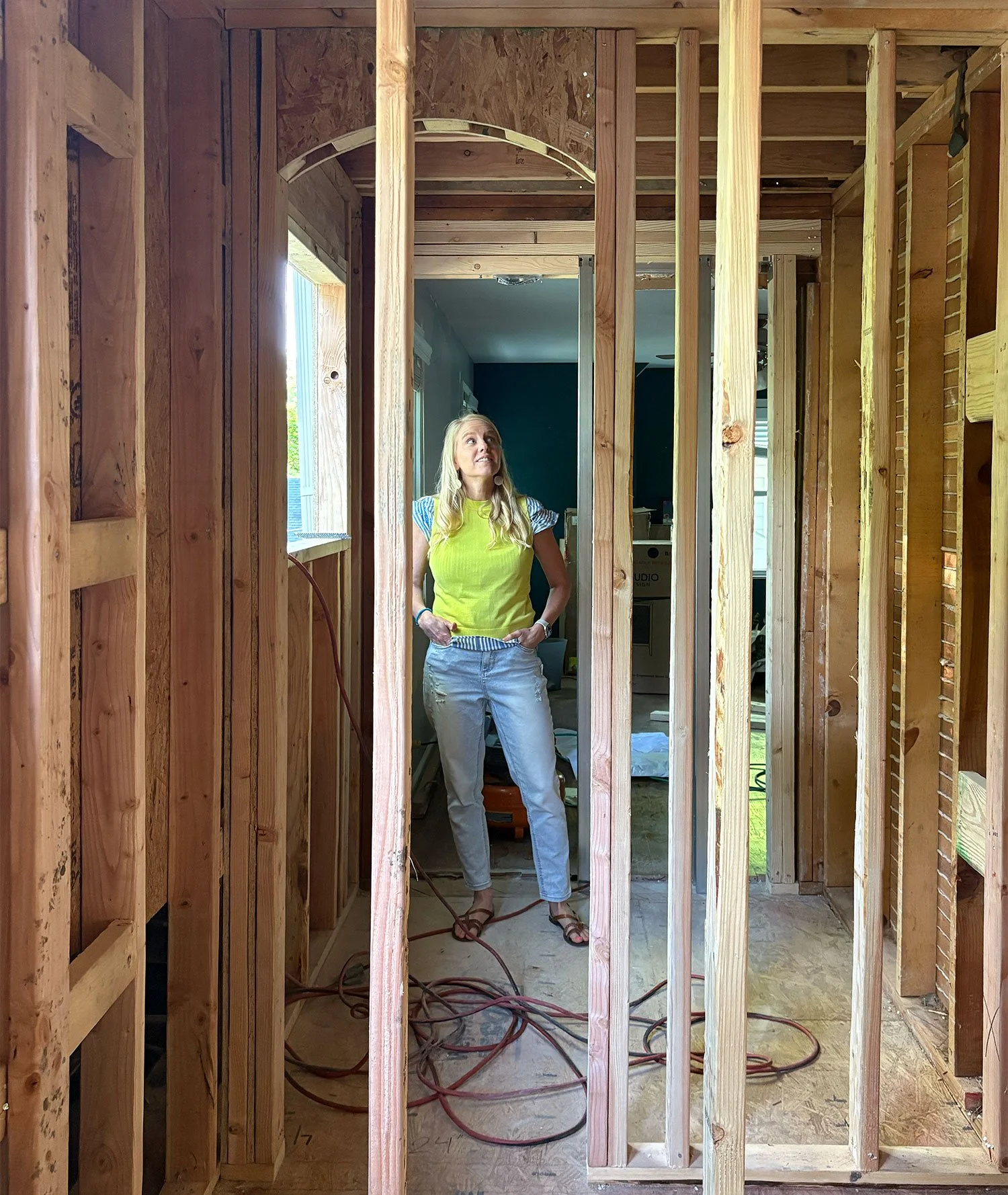 Interior designer Erica Kay Thowe standing on a residential construction site in Kansas City, performing an on-site design review of framing and structural details for a whole-home remodeling project.