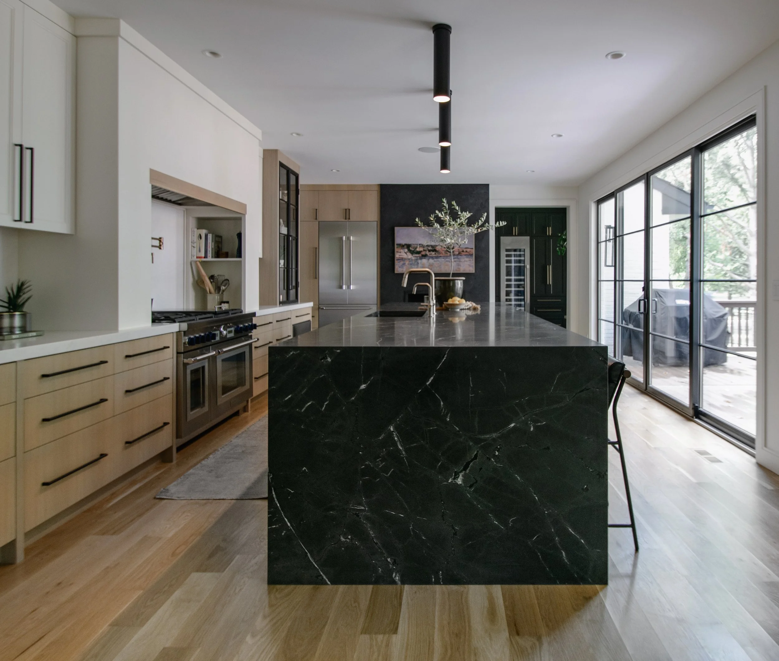 Luxury kitchen by Erica Kay Design & Remodeling, featuring rift sawn white oak cabinets, range alcove, and large island with waterfall end with Saratoga Quartzite