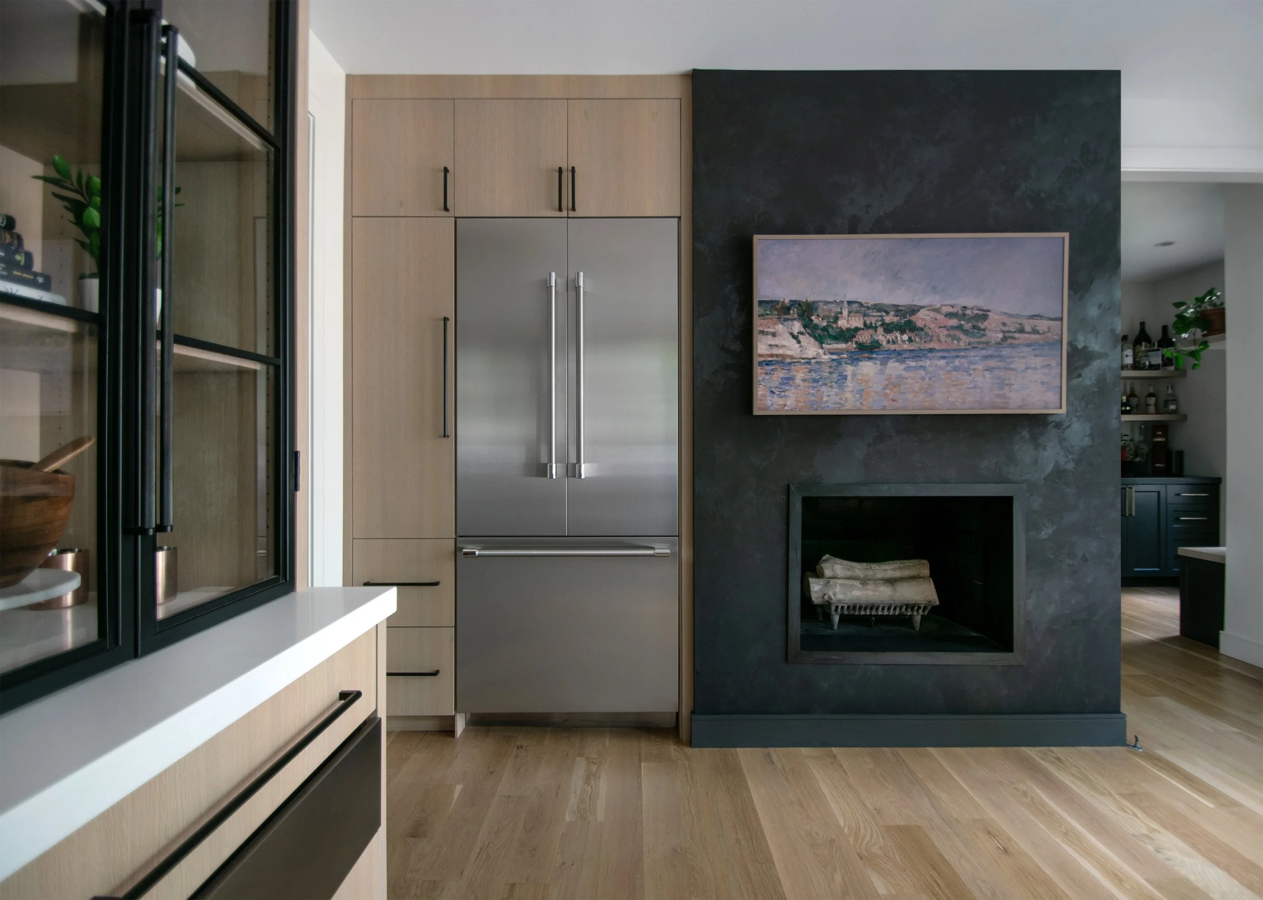A bright, luxury kitchen remodel in Kansas City by Erica Kay Design & Remodeling featuring rift sawn white oak cabinets and faux suede fireplace wall.