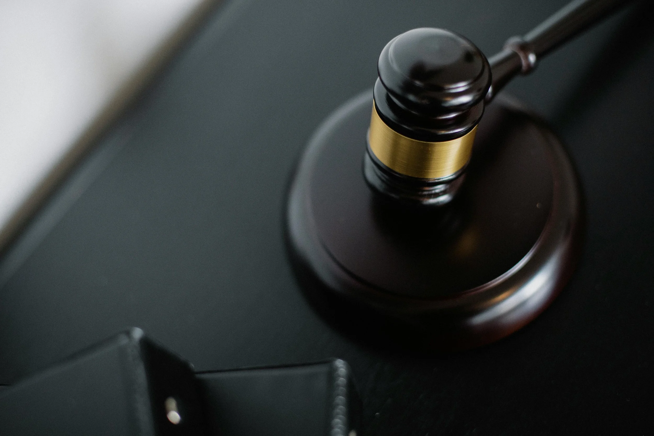 Close-up of a wooden gavel with a gold band resting on a sound block