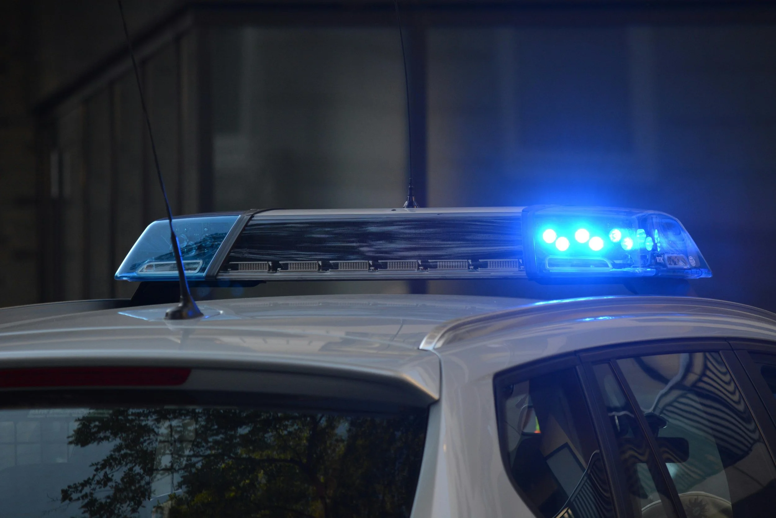 Police car with flashing blue lights on the roof.