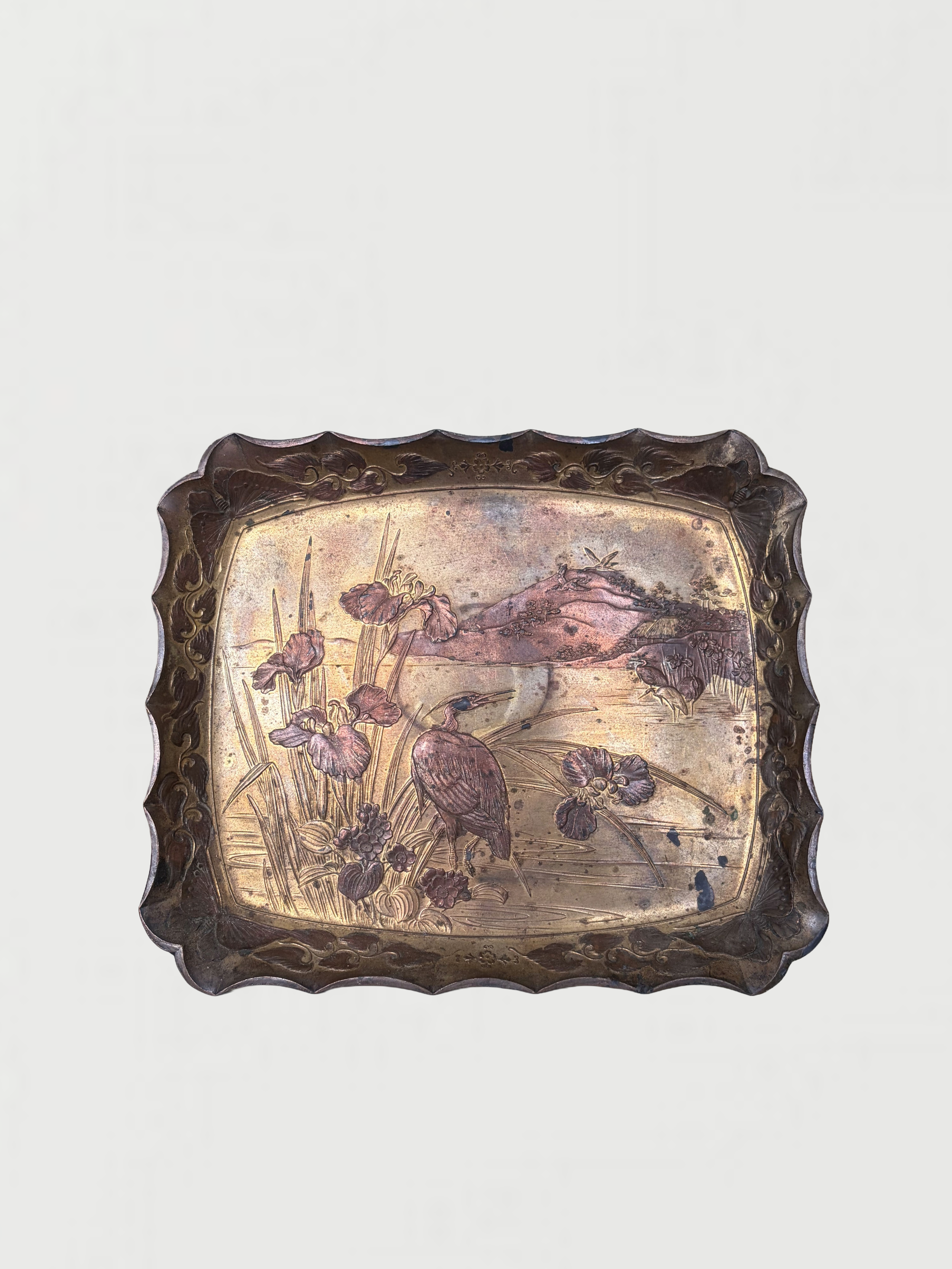 Decorative metal tray with a floral and landscape design featuring birds, with a scalloped edge.