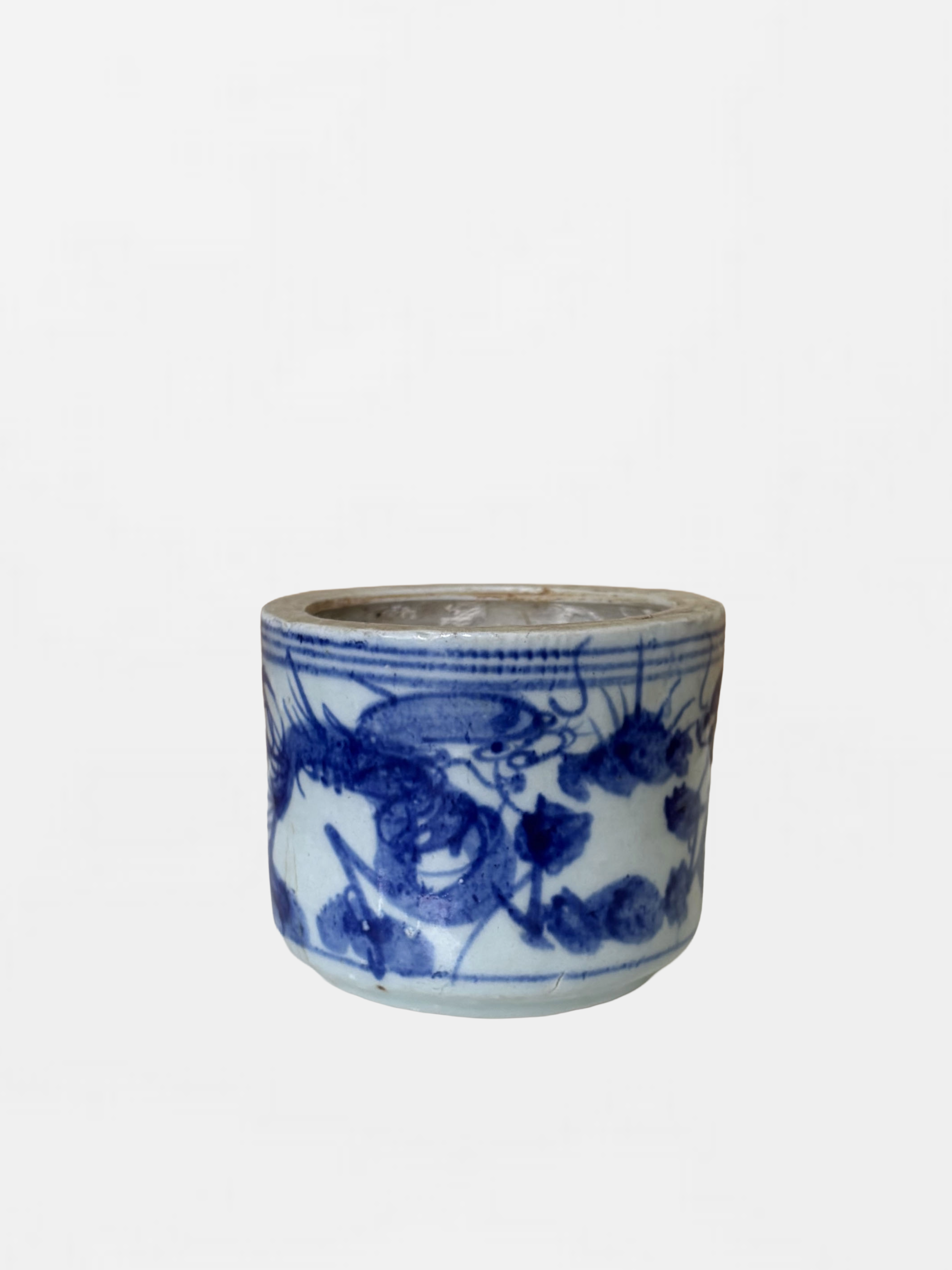 A white ceramic cup with blue hand-painted floral and geometric patterns.