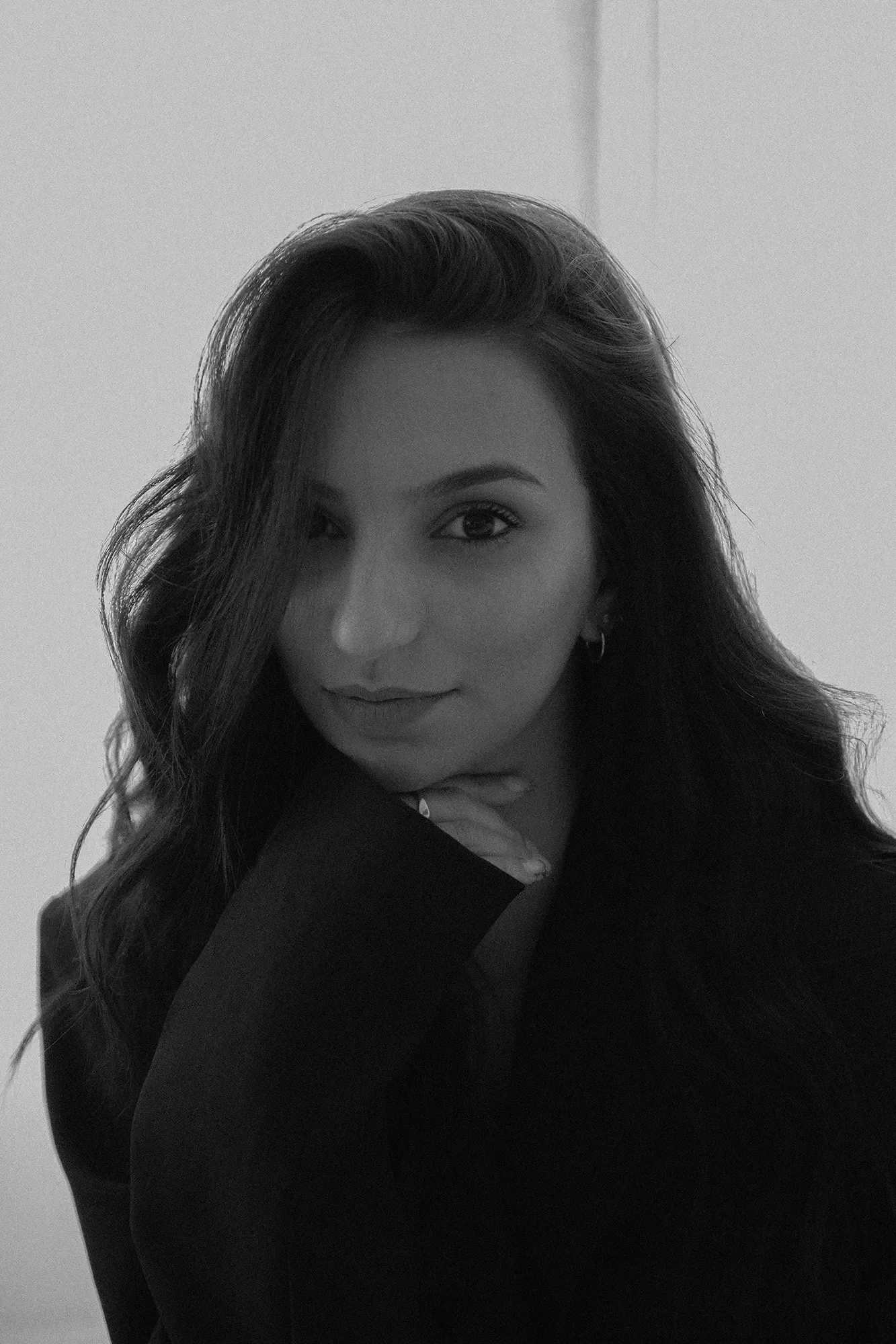 Portrait en noir et blanc d'une femme avec de longs cheveux bouclés portant un blazer.
