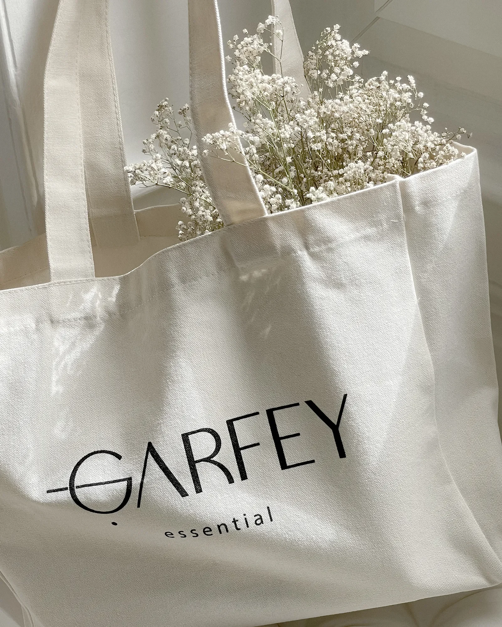 Un sac blanc avec des fleurs blanches à l'intérieur et le logo Garfey