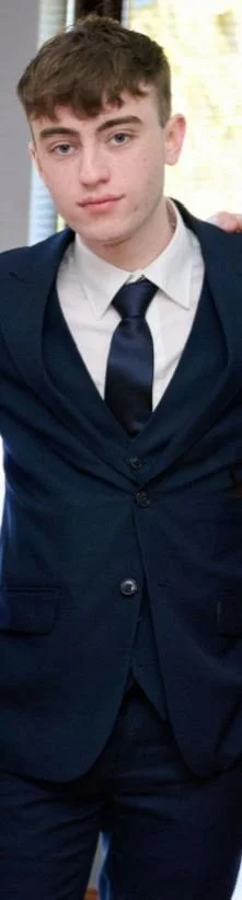 A person with short brown hair looks to camera.