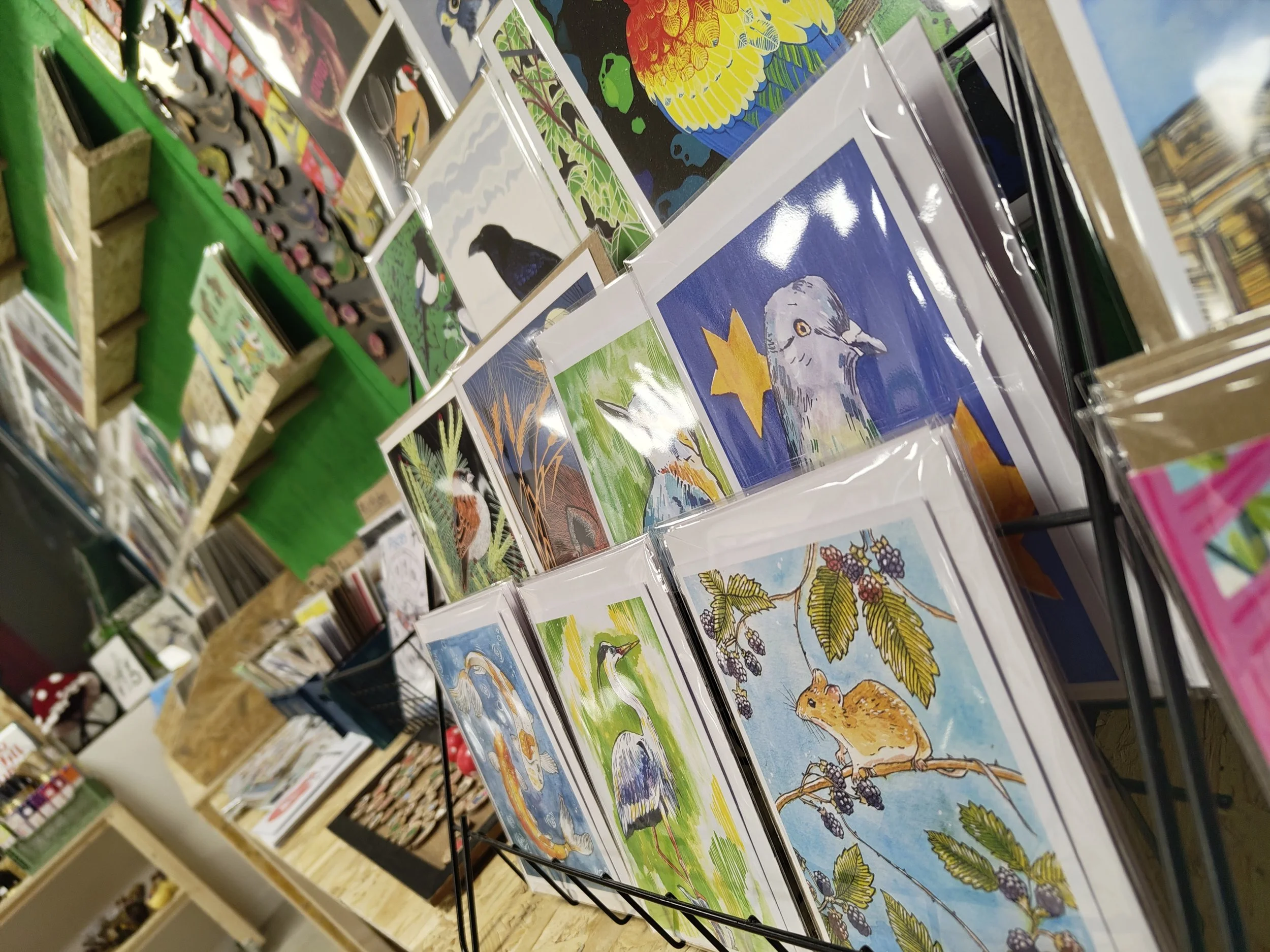 Display of colorful bird and animal illustrations including a duck, a bird, a hamster, and a fox, at an art or craft market.