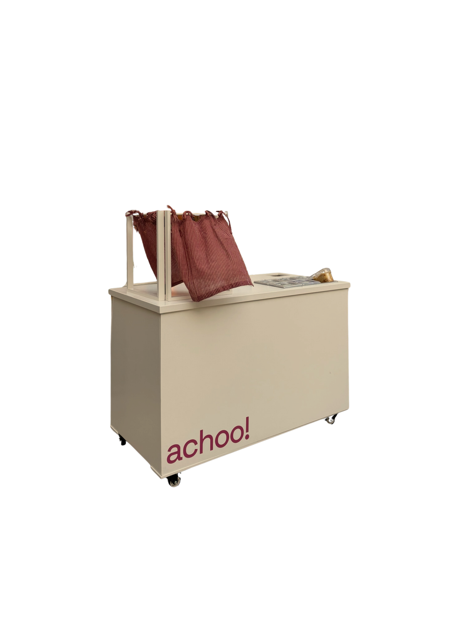 A white mobile shaved ice bar with the word 'achoo!' printed in red on the front, featuring bins for toppings and a red curtain to securely cover the machine that makes the fresh shaved ice