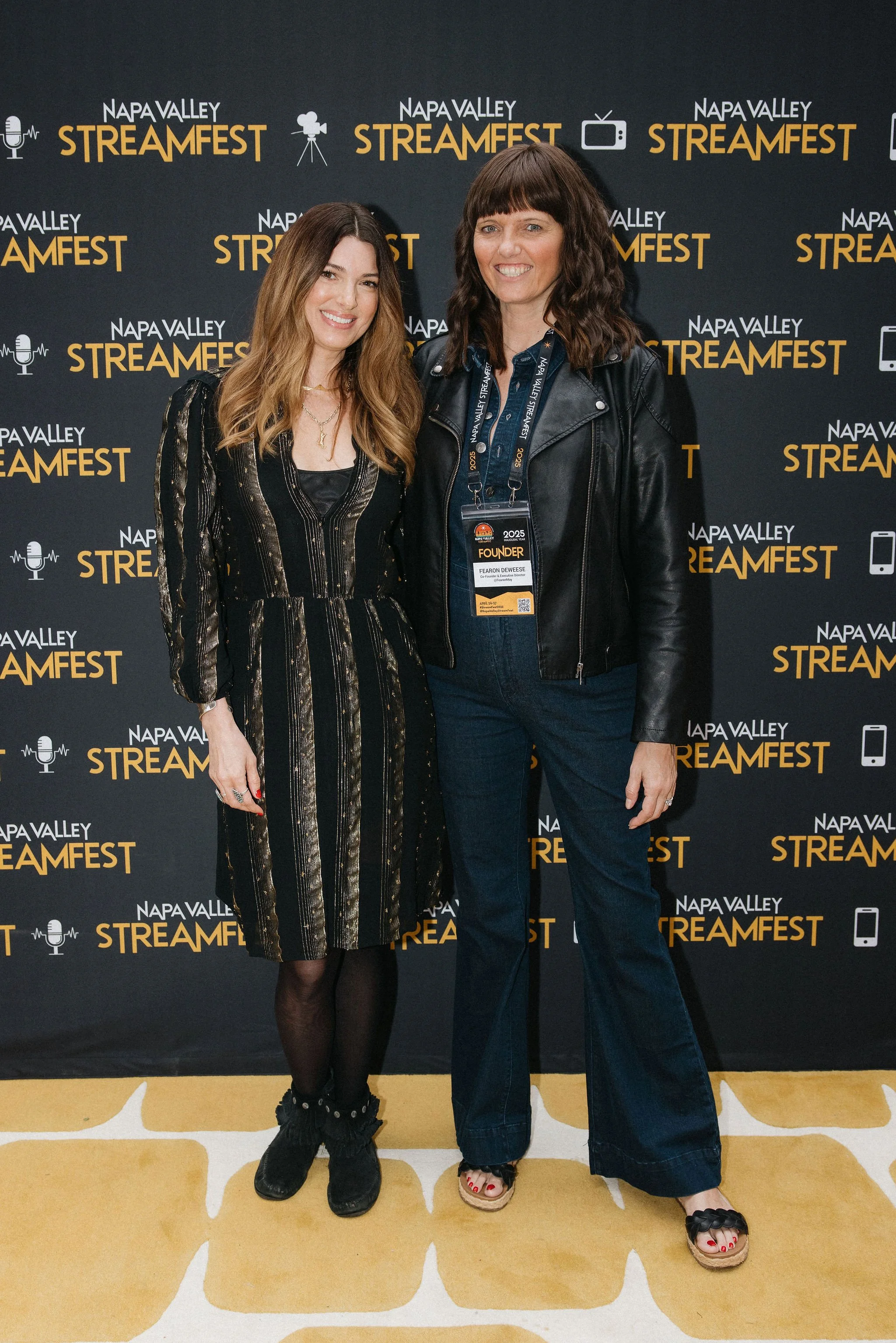 Two women standing in front of a backdrop with 'Napa Valley Streamfest' written multiple times. Aria Pullman Avenue A Films Founder Writer Director Fearon DeWeese Napa Valley Strem Fest  Founders Both are smiling and posing for the camera.