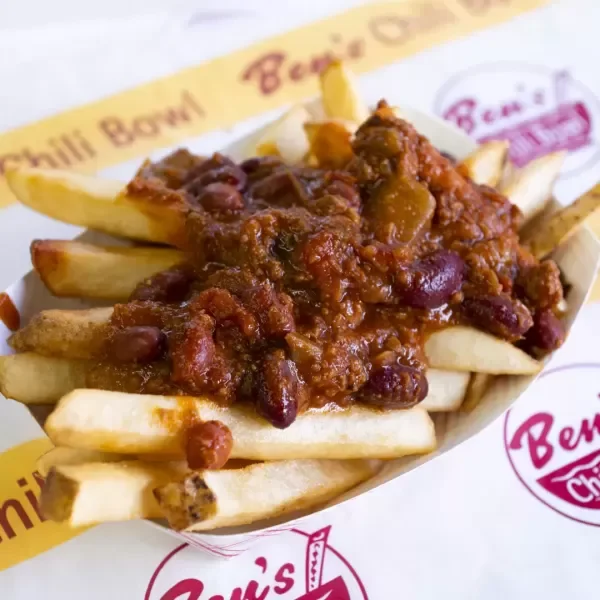French fries topped with chili and beans in a paper boat from Ben's Chili Bowl.