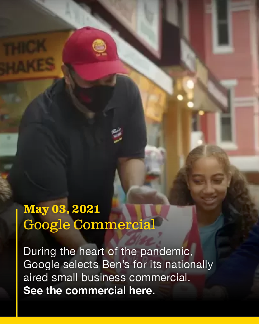 A young girl receiving a bag from a worker at a Ben's restaurant during the pandemic, with a sign for thick shakes in the background.