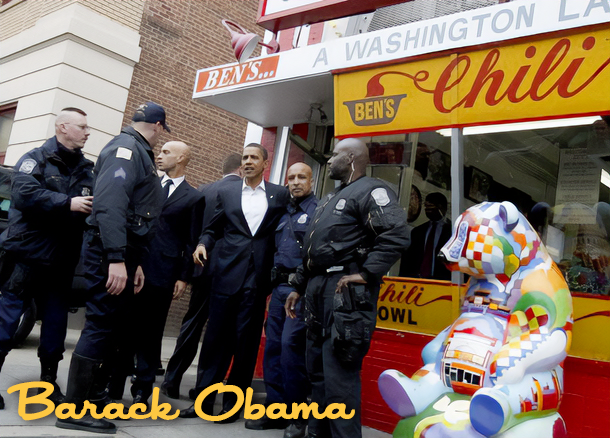 A group of police officers and a man in a suit standing in front of a chili stand with a colorful stuffed animal toy on display.