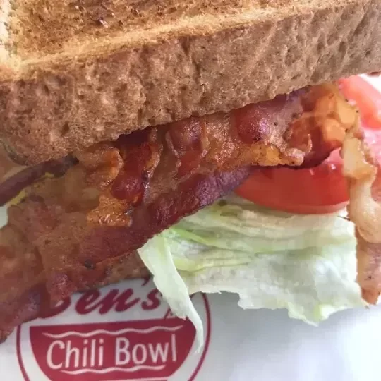 Close-up of a BLT sandwich with bacon, lettuce, tomato, and whole wheat bread.