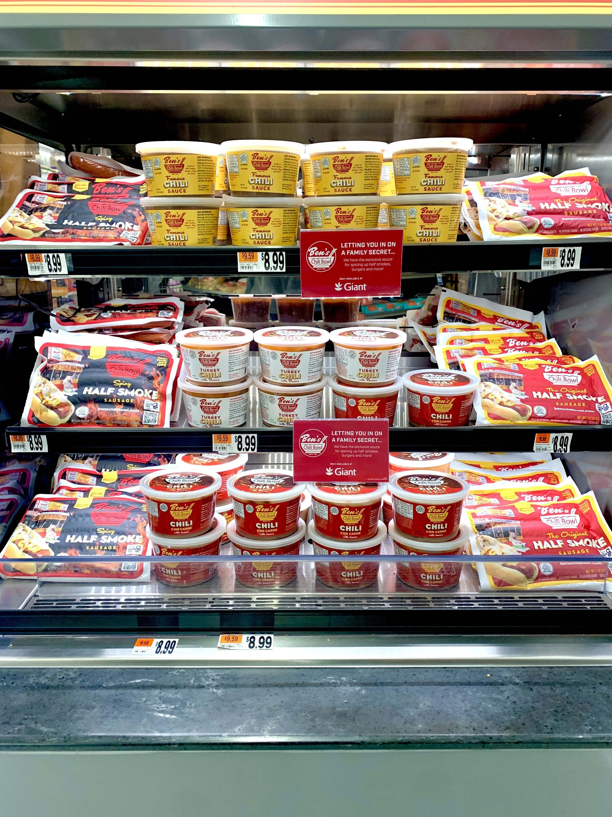 Shelves displaying Ben's chili products, including containers of chili in different flavors and packages of chili sausages, with price tags of $8.99.