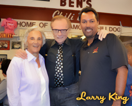 Three men smiling and posing together inside a restaurant with signs and decorations in the background.