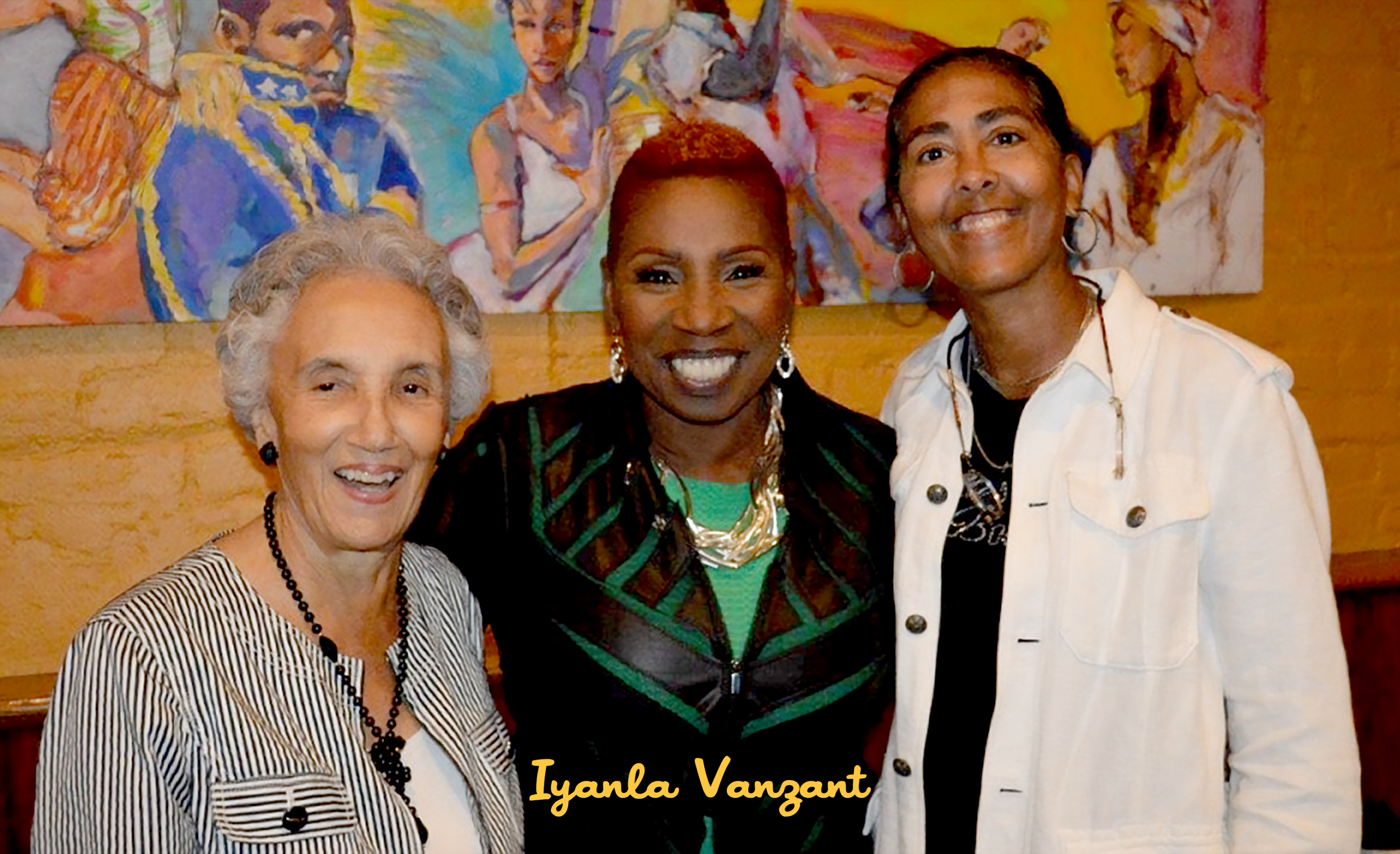 Three women standing close together and smiling for a photo in front of a colorful abstract painting, with the name Iyanla Vanzant written at the bottom.