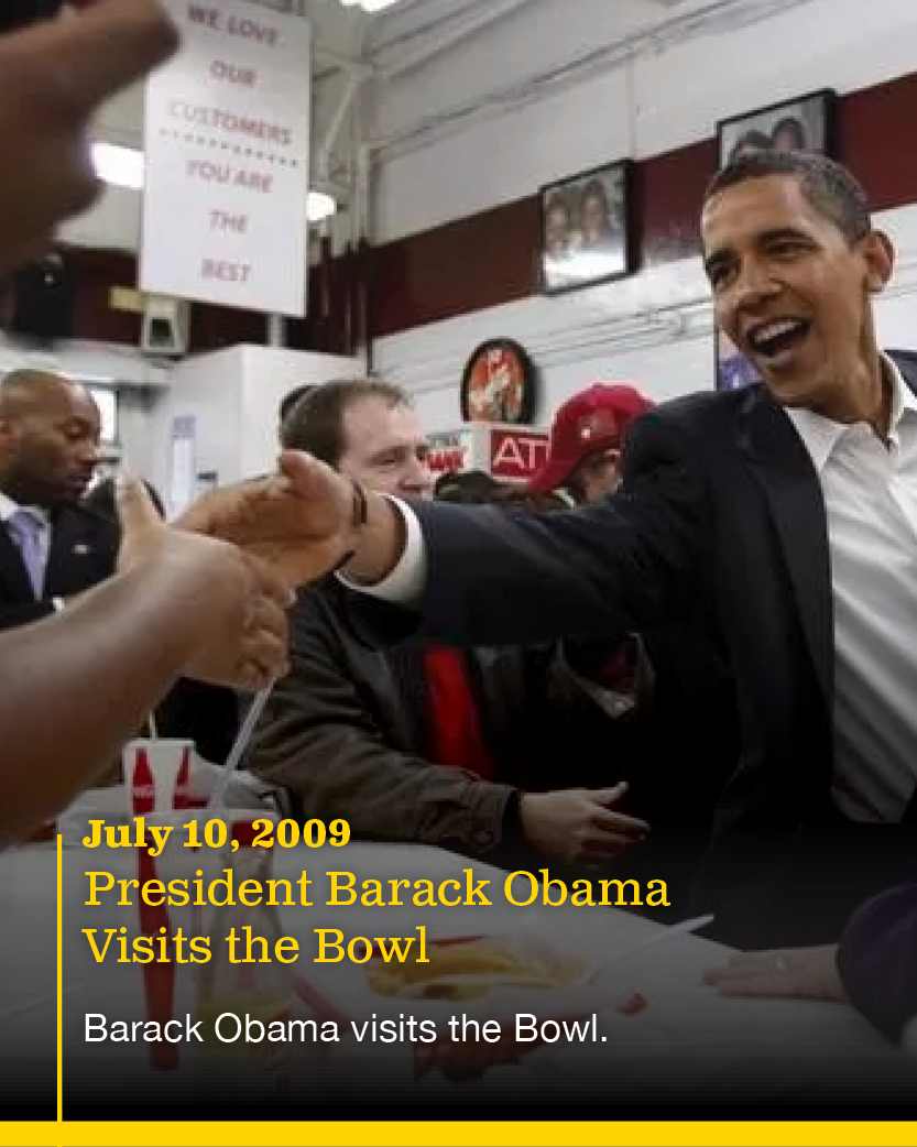 President Barack Obama smiling and greeting people at a diner or restaurant, engaging in handshakes during a visit on July 10, 2009.