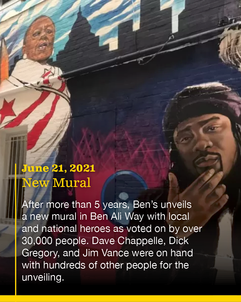 A mural featuring portraits of American figures, including a woman with the American flag design on her clothing and a man with dreadlocks, along with skyline imagery in the background. The mural is accompanied by an overlay text describing the unvei