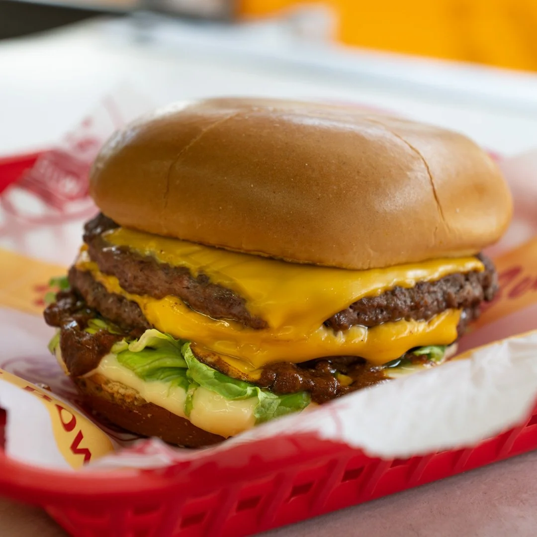 Close-up of a cheeseburger with lettuce, cheese, and beef patty in a bun, in a red basket.