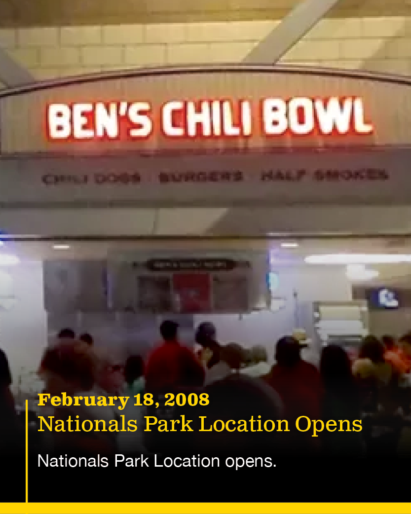 Sign for Ben's Chili Bowl restaurant inside a restaurant or food court area with customers standing in line.