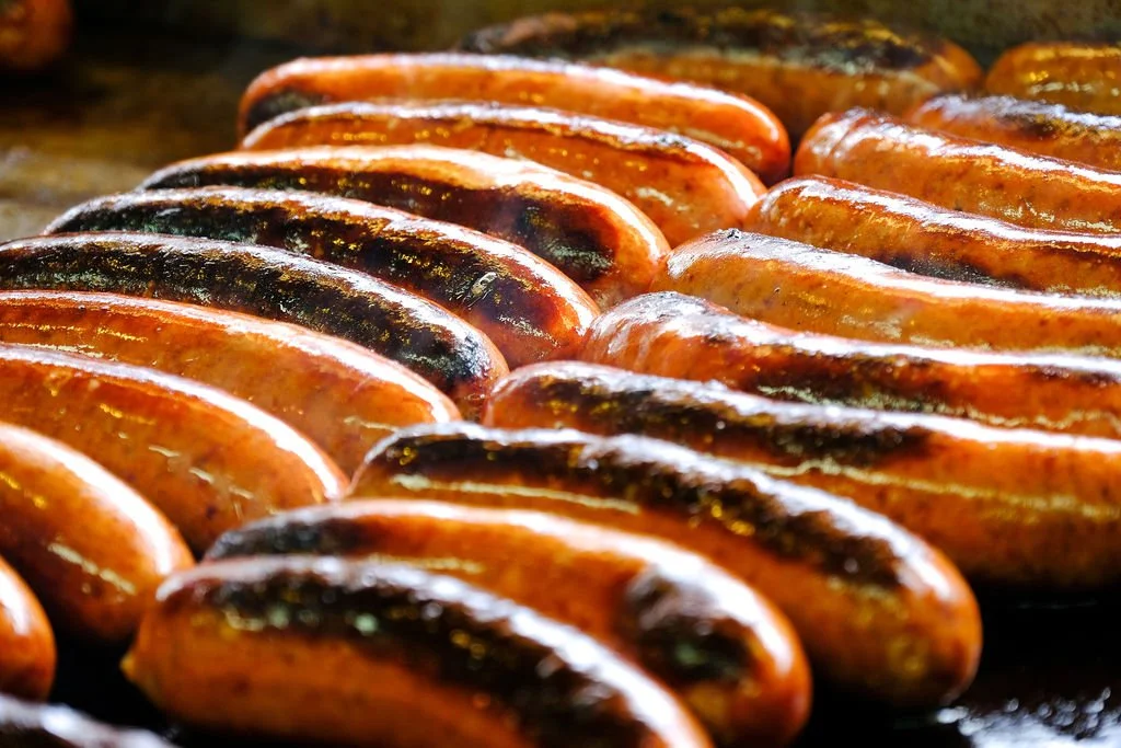 Close-up of sizzling sausages cooking on a grill.