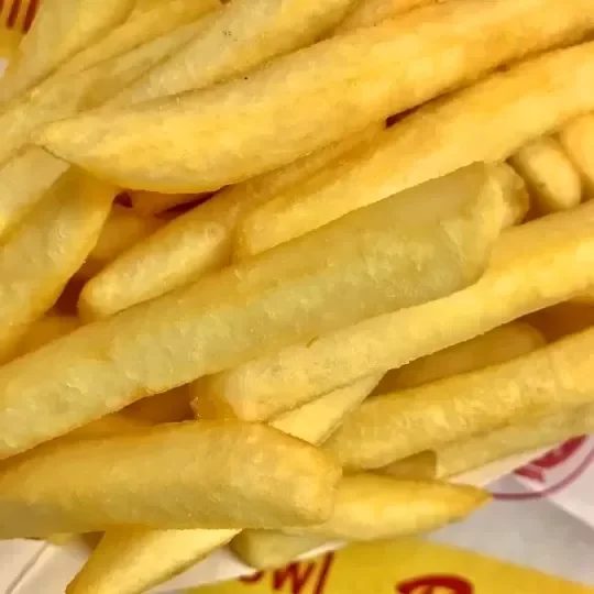 Close-up of French fries in a paper fast food container.
