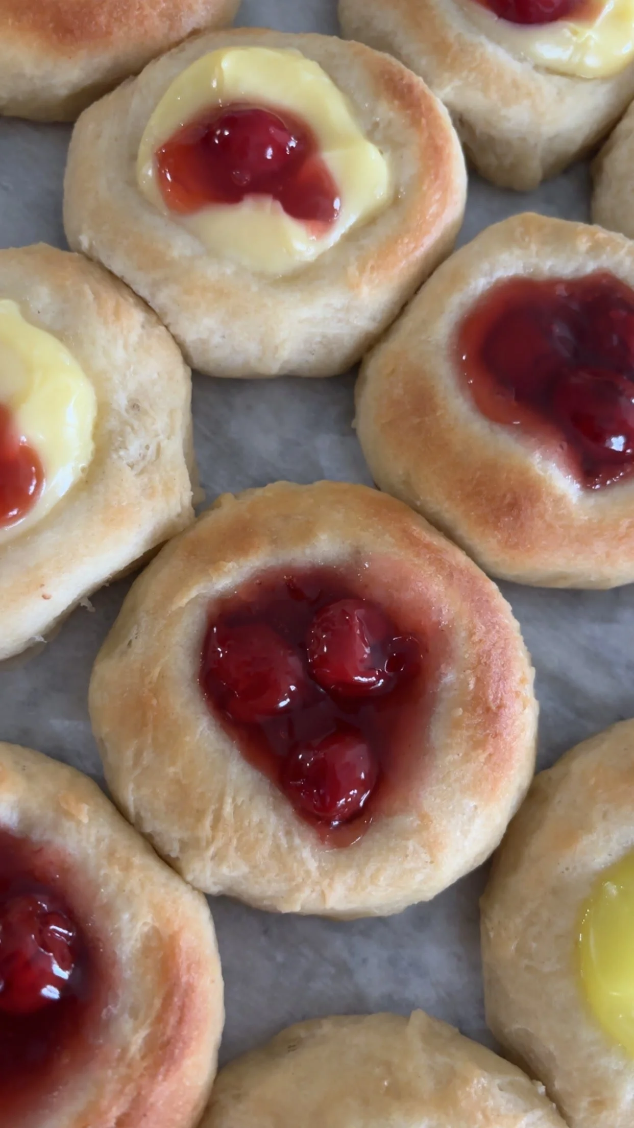 Assorted kolache pastries with cherry and custard fillings.