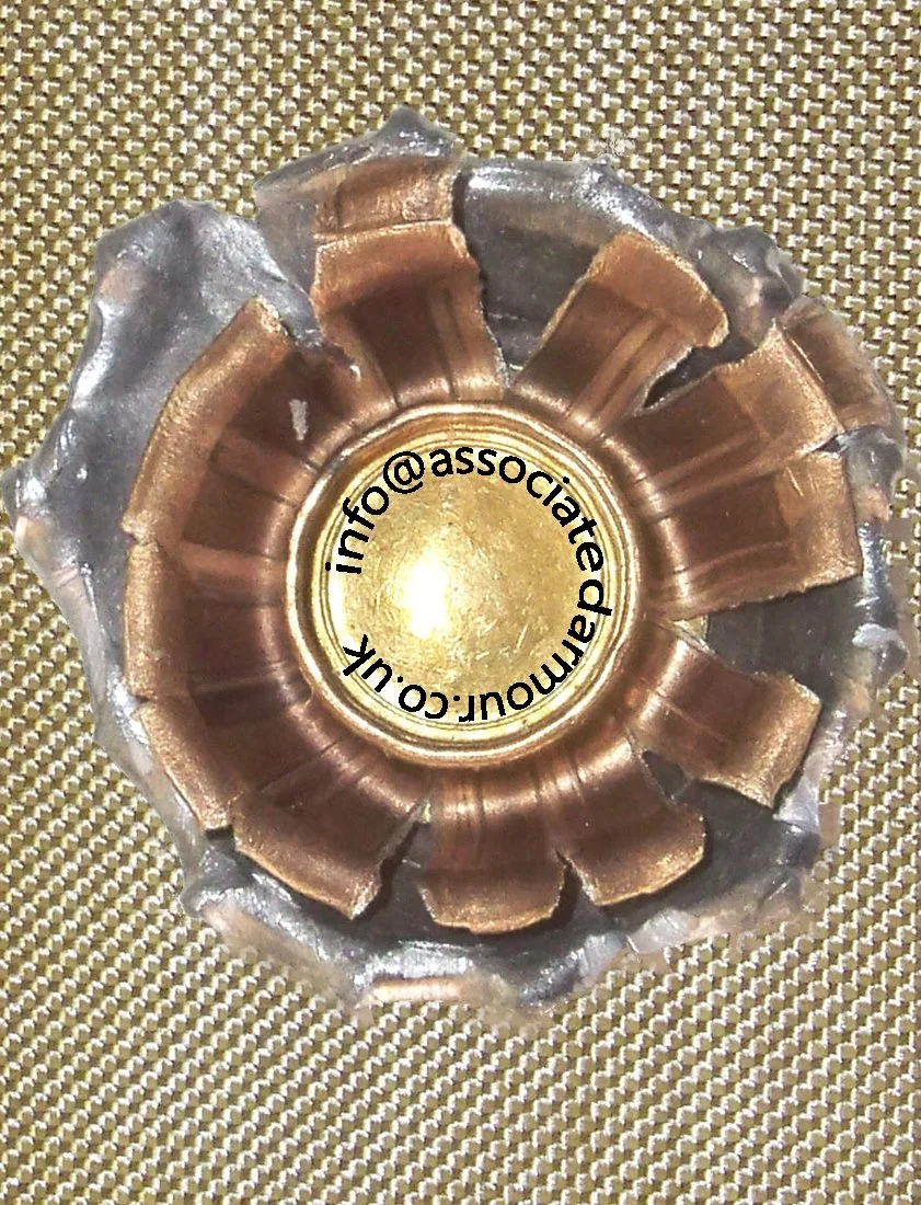 A close-up view of a metallic object with a circular shape, featuring gold and silver coloring, and text inside reading "info@associatedaul.com" written in black that is slightly curved.